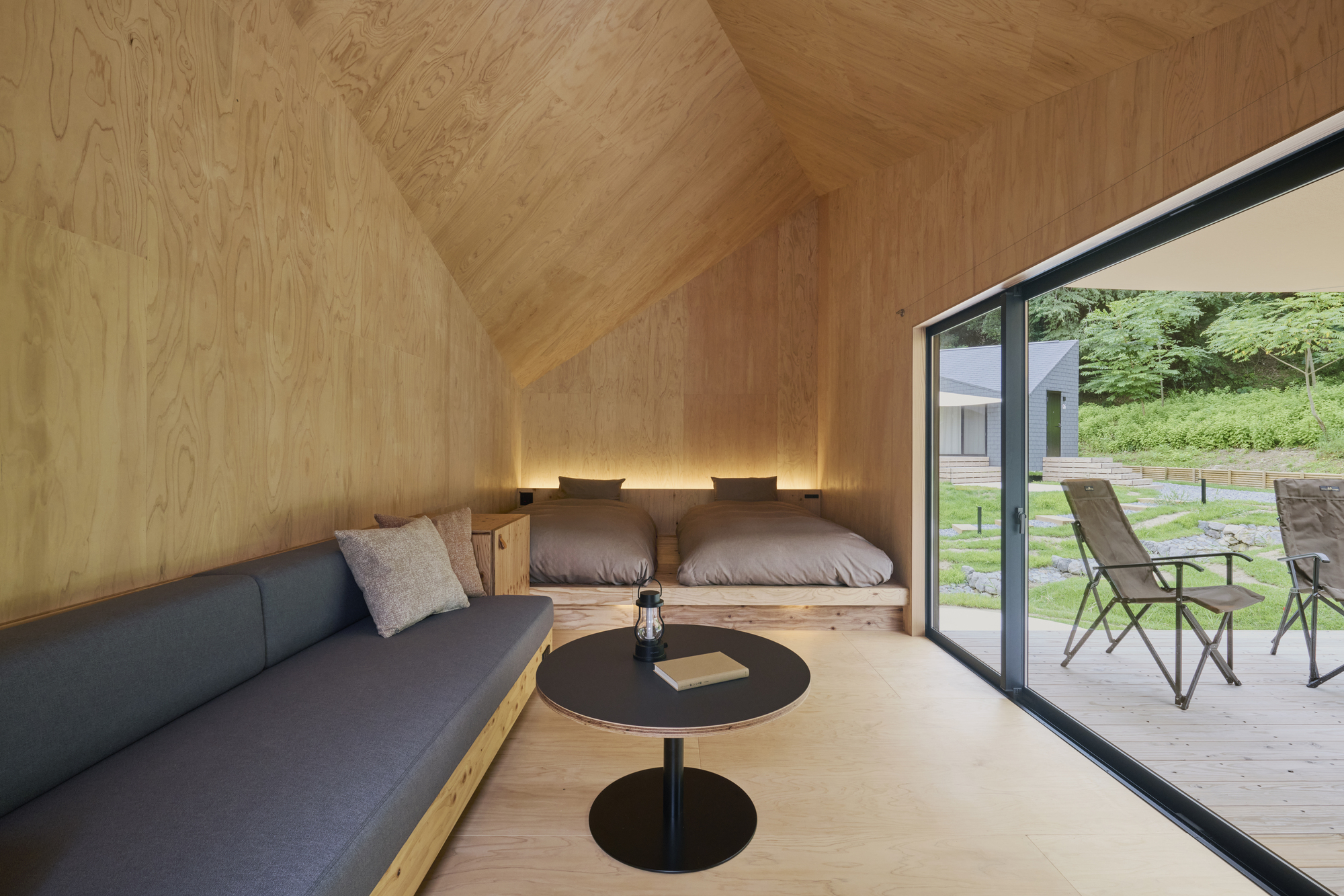 Plywood-lined sleeping loft with built-in platform bed and sliding glass door to deck