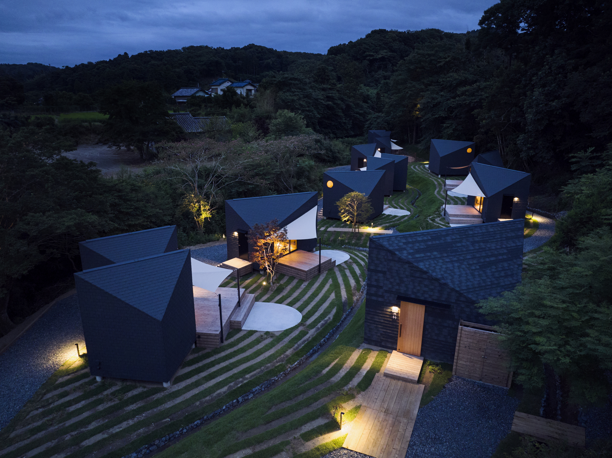 Elevated night view of the cluster of illuminated volumes scattered across the sloped landscape