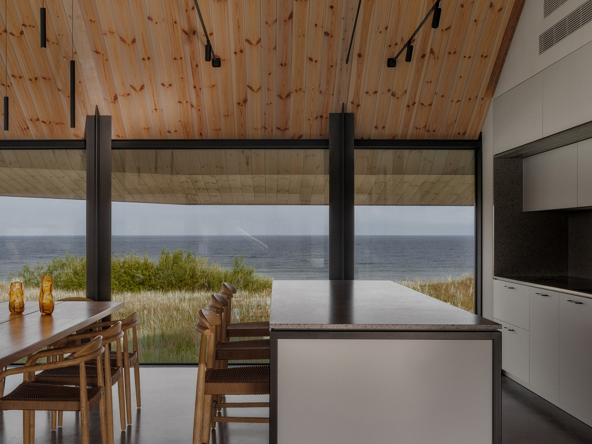 Open dining area with timber ceiling looking out to infinity pool and distant water horizon