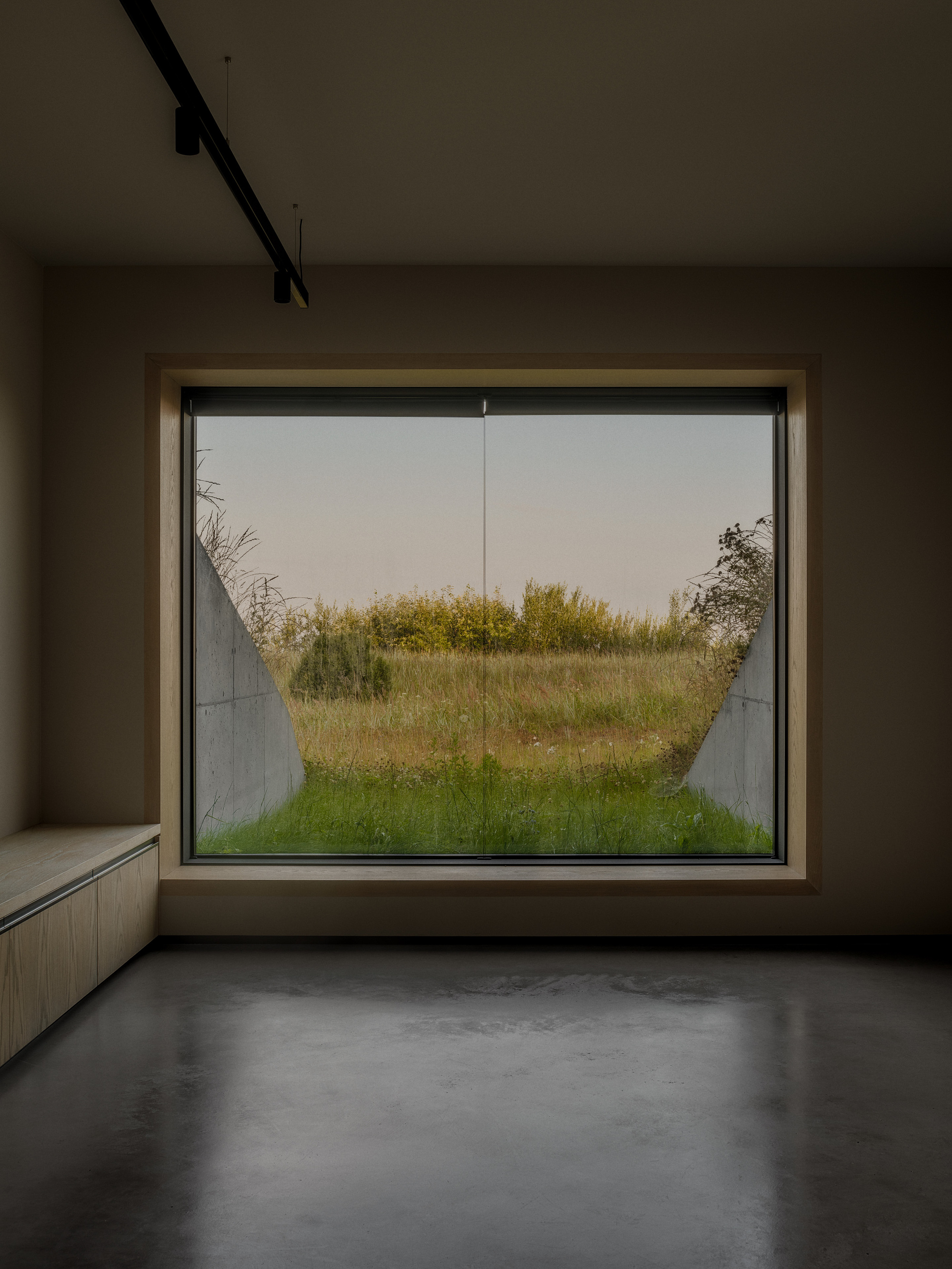 Large picture window framing a view of prairie grasses beneath an overcast sky