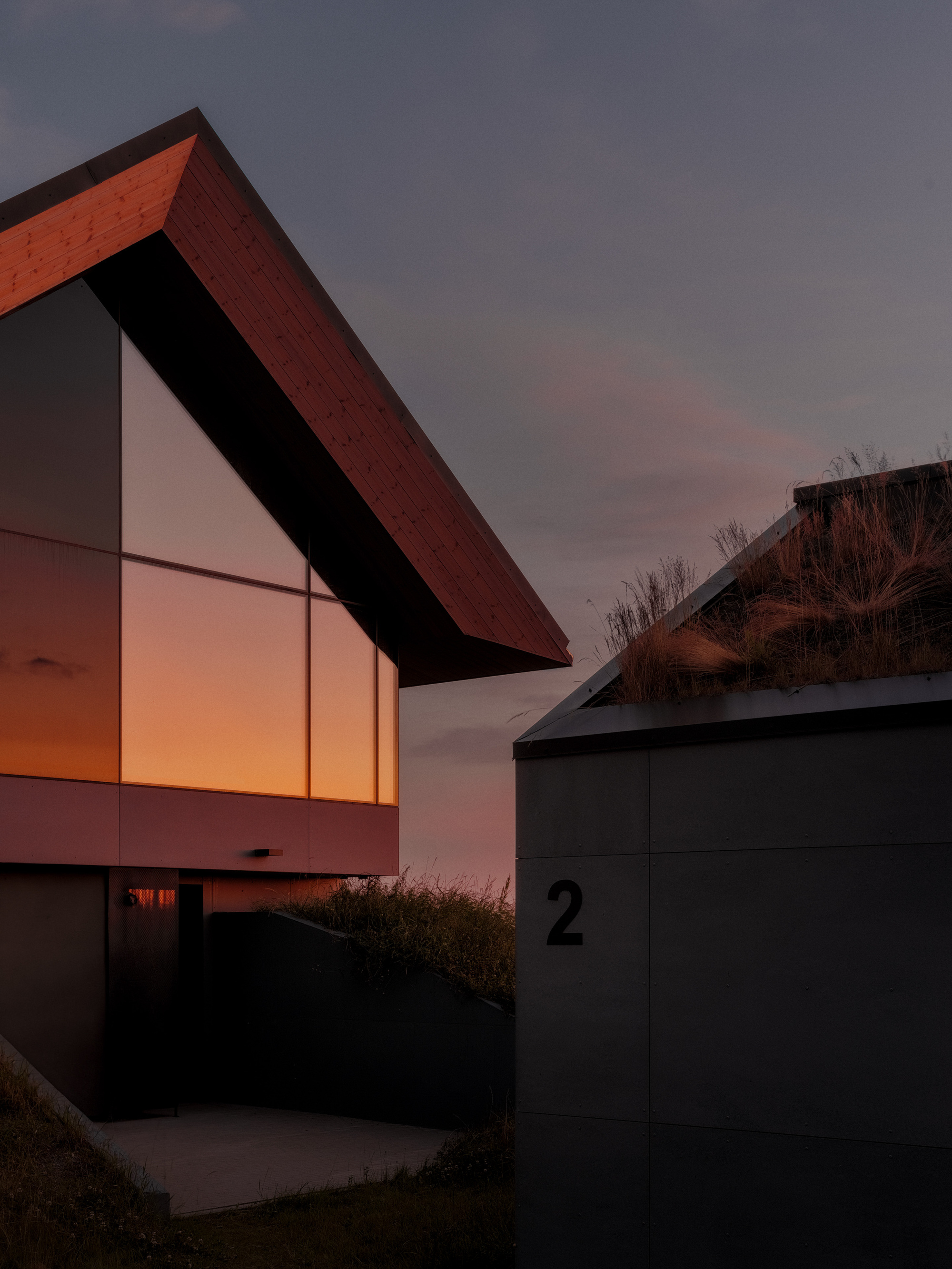 Gabled facade with timber cladding and glowing interior light at twilight