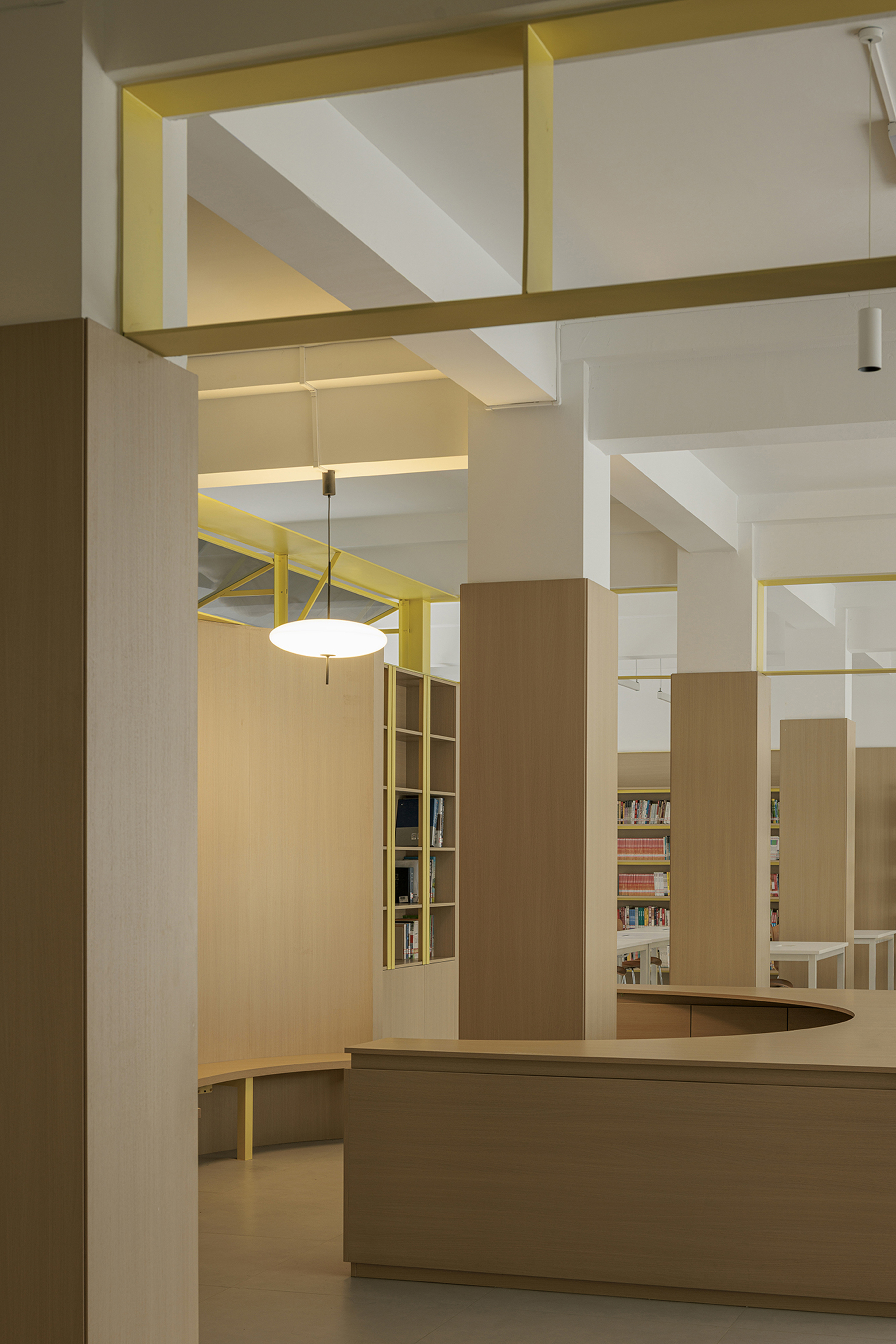 Interior circulation desk with yellow-framed ceiling coffers and light wood built-in shelving