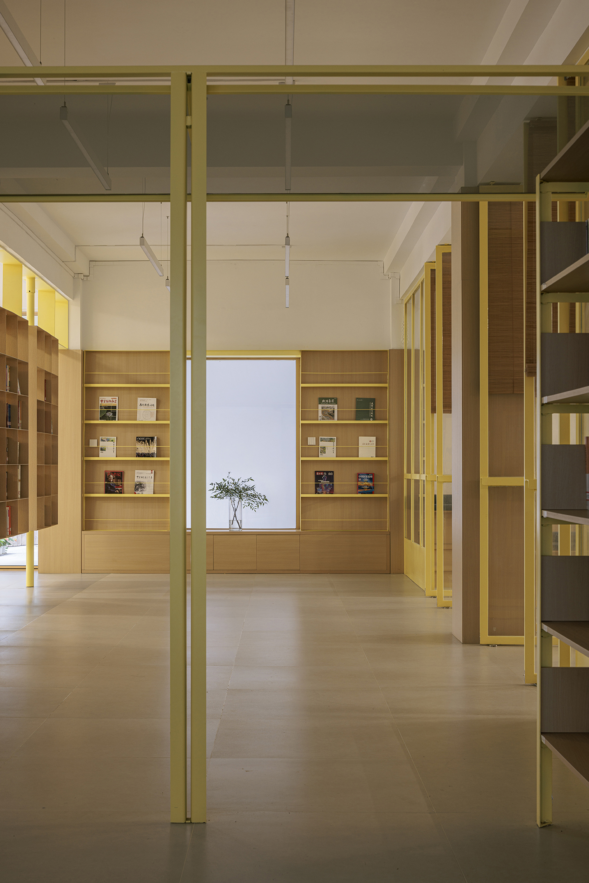 Library interior with yellow steel structural columns and light oak floor-to-ceiling bookshelves