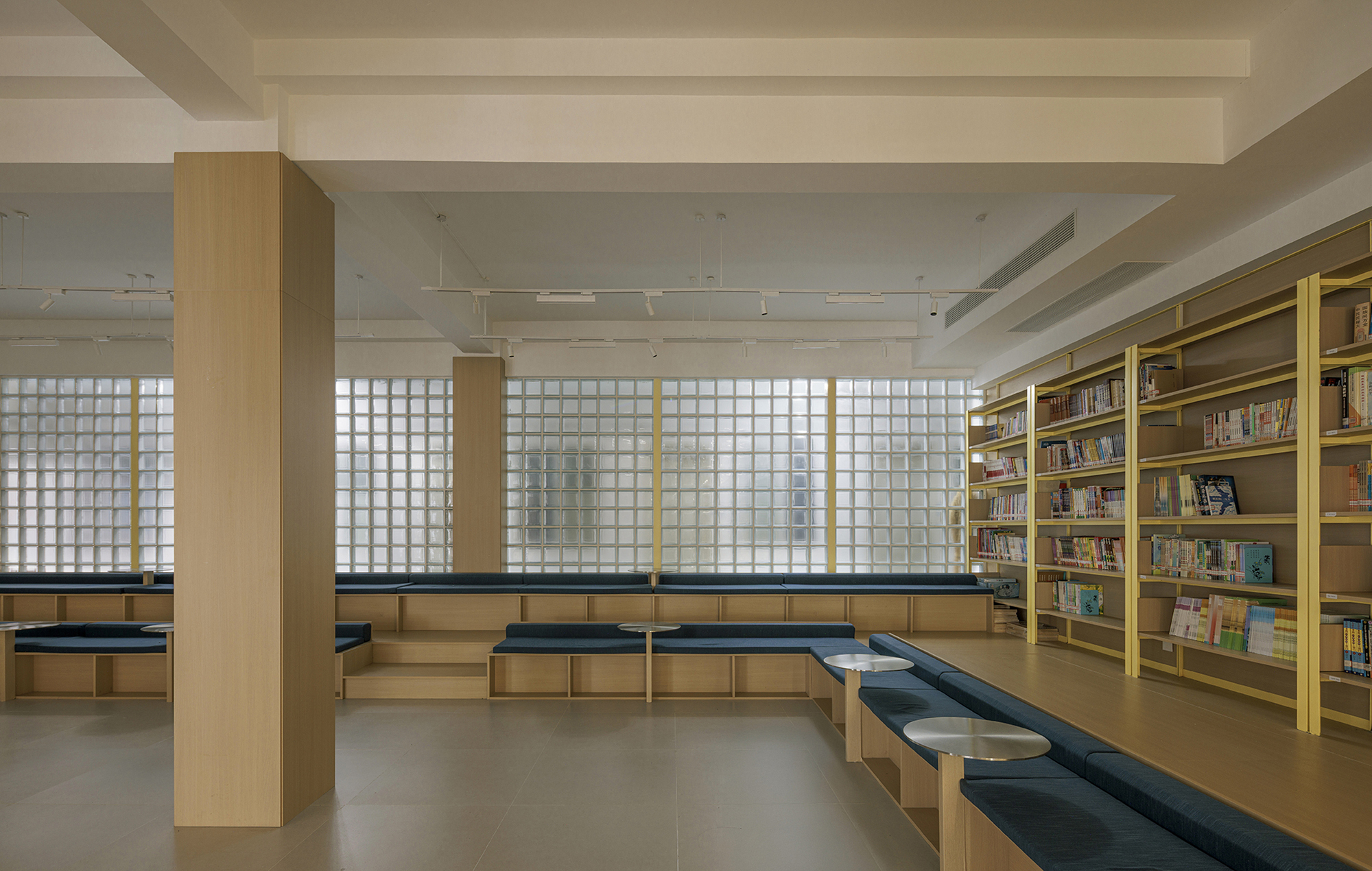 Reading area with stepped seating below translucent glass block windows filtering daylight