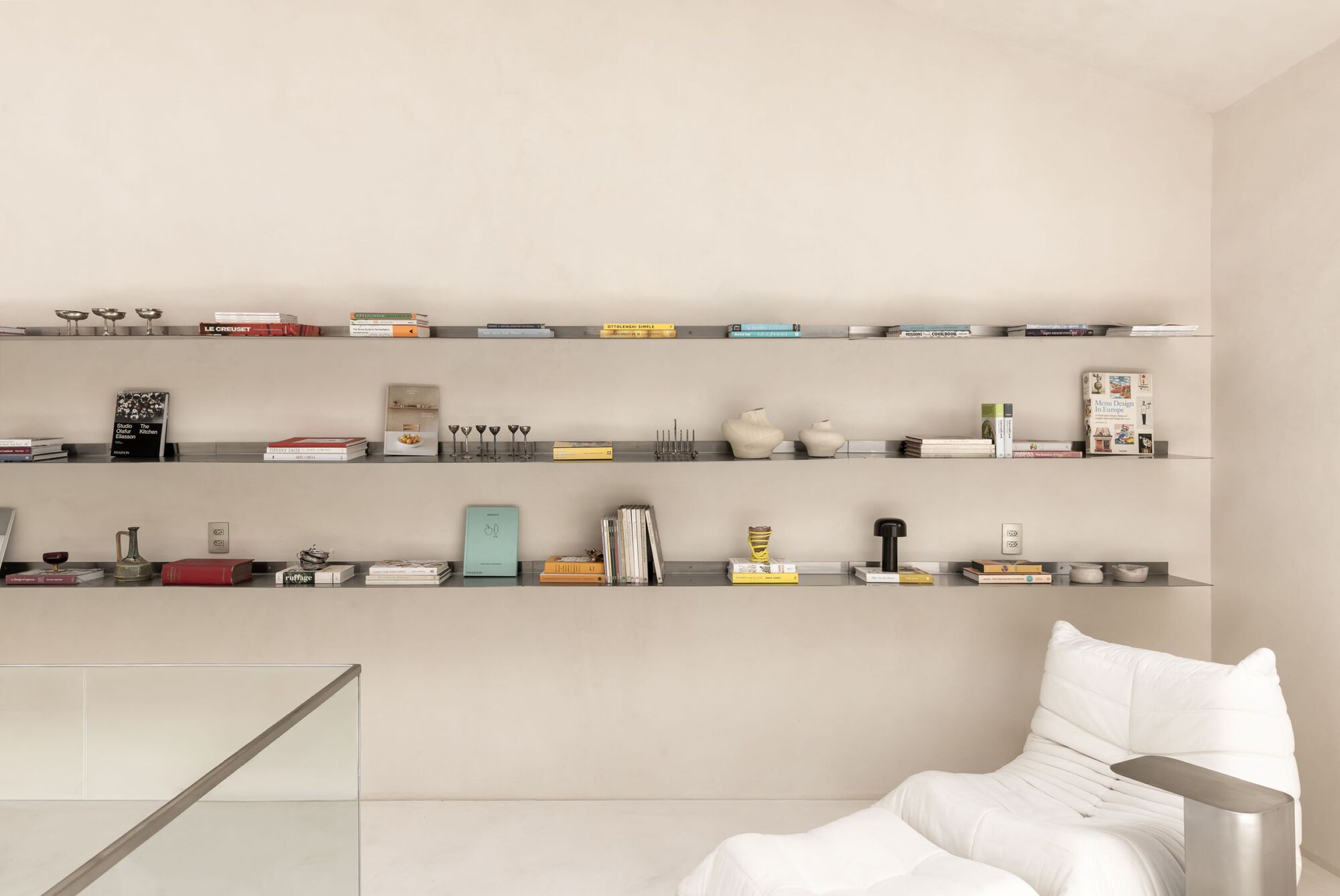 Built-in shelving spanning the wall displaying books and glassware above a white sofa