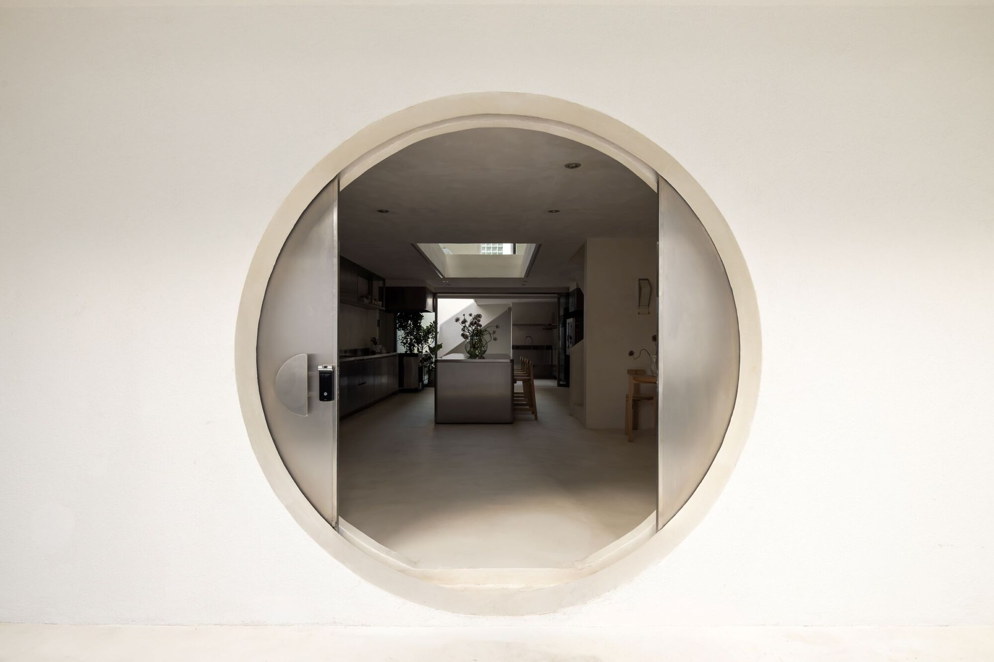 Circular plaster portal framing a view through to the kitchen and skylight beyond