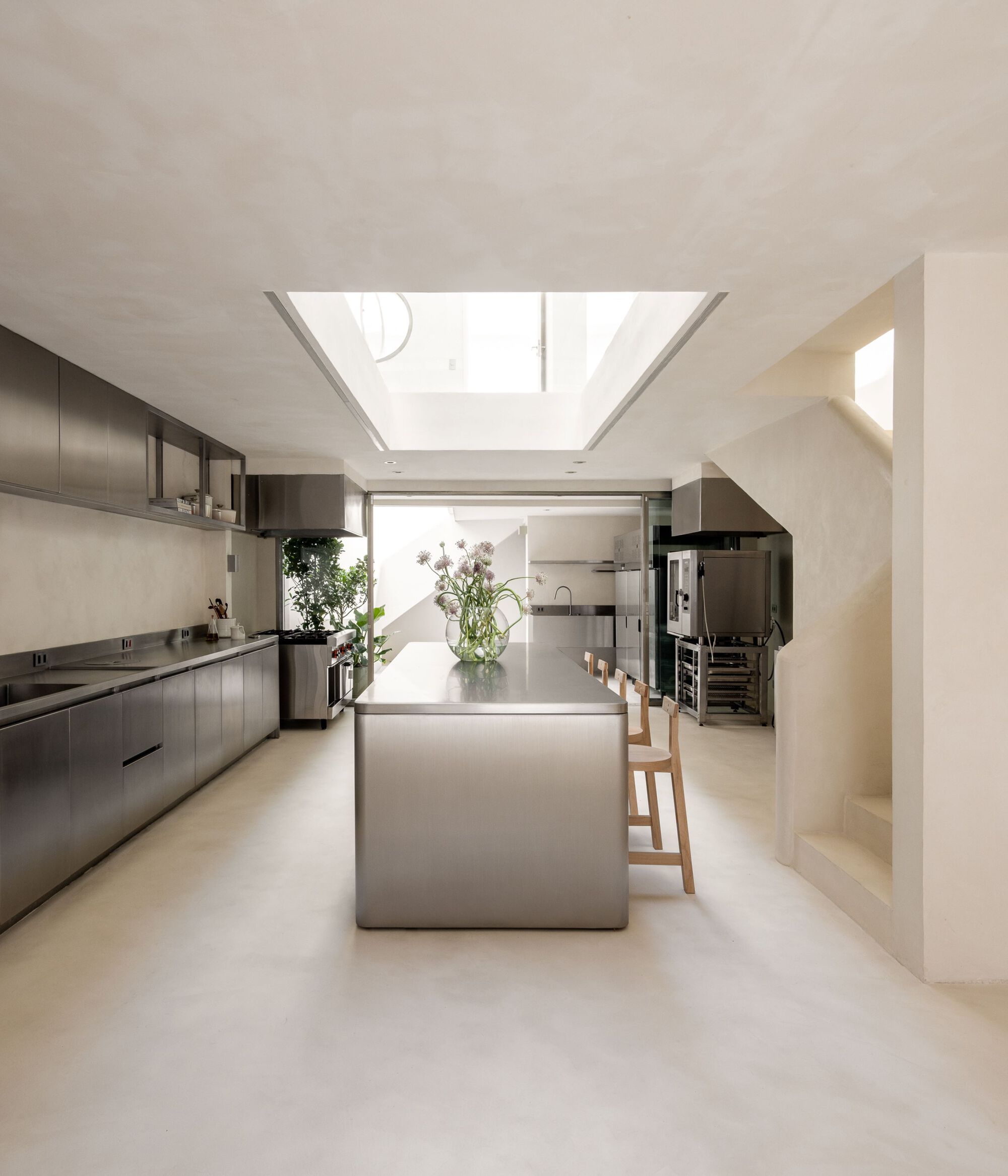 Galley kitchen with stainless steel island and cabinetry beneath central skylight