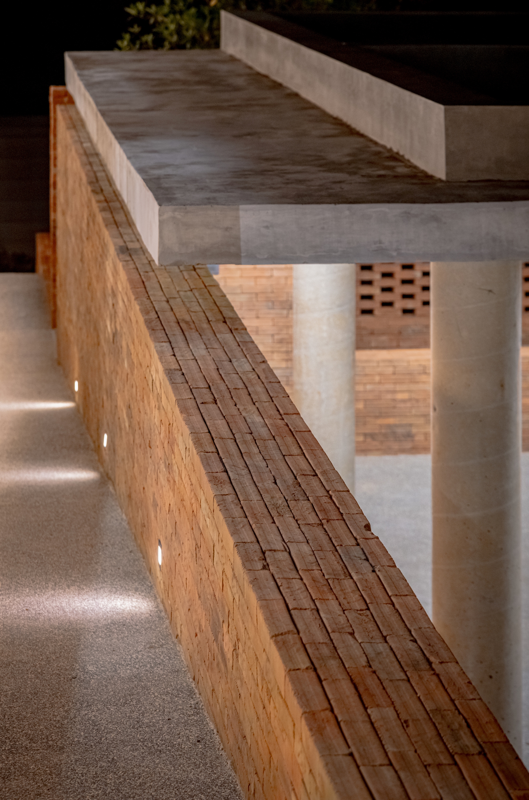 Concrete bench detail with brick base and recessed lighting at night