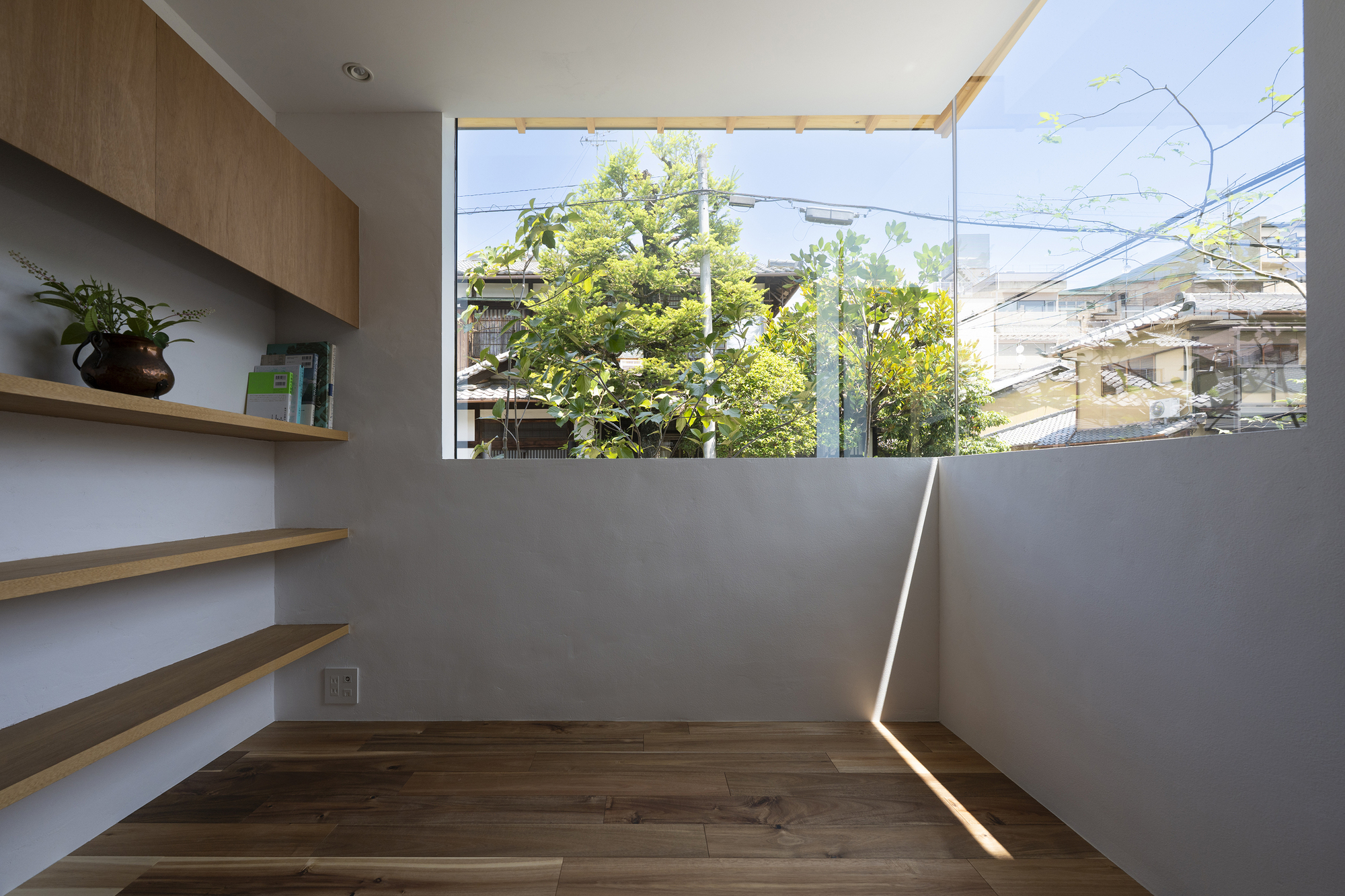 Corner study nook with timber shelving and high clerestory window overlooking neighboring rooftops
