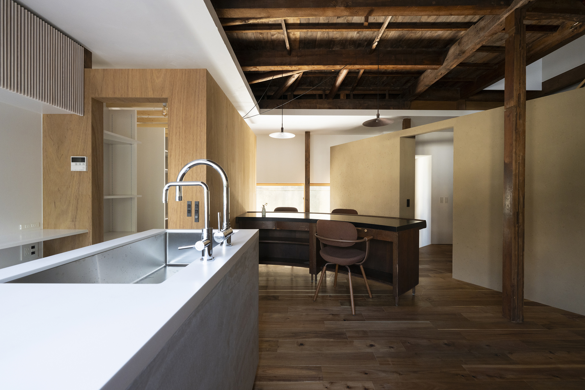 Kitchen island with white countertop and dining area beneath exposed timber beams and joists
