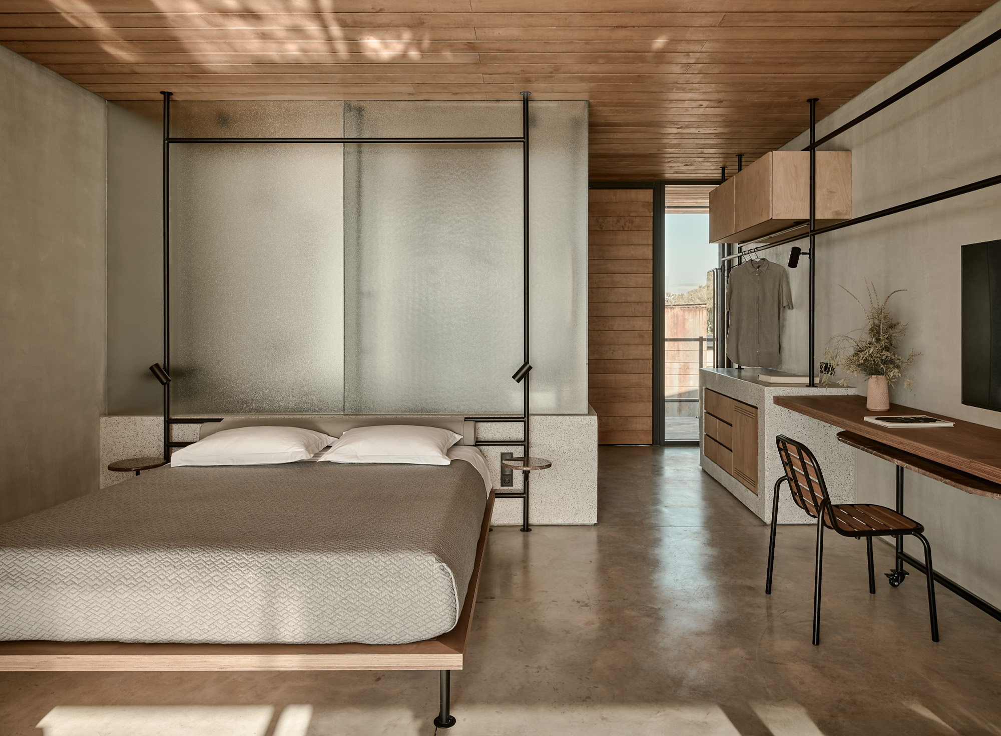 Bedroom with translucent panel headboard and concrete partition beneath slatted timber ceiling