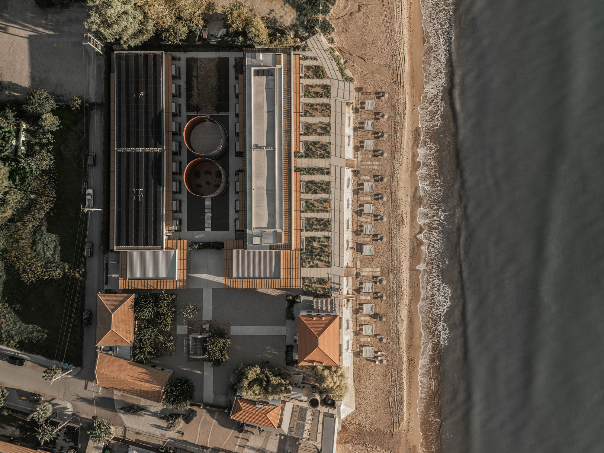 Drone view showing rooftop pools and timber canopy structure along the shoreline