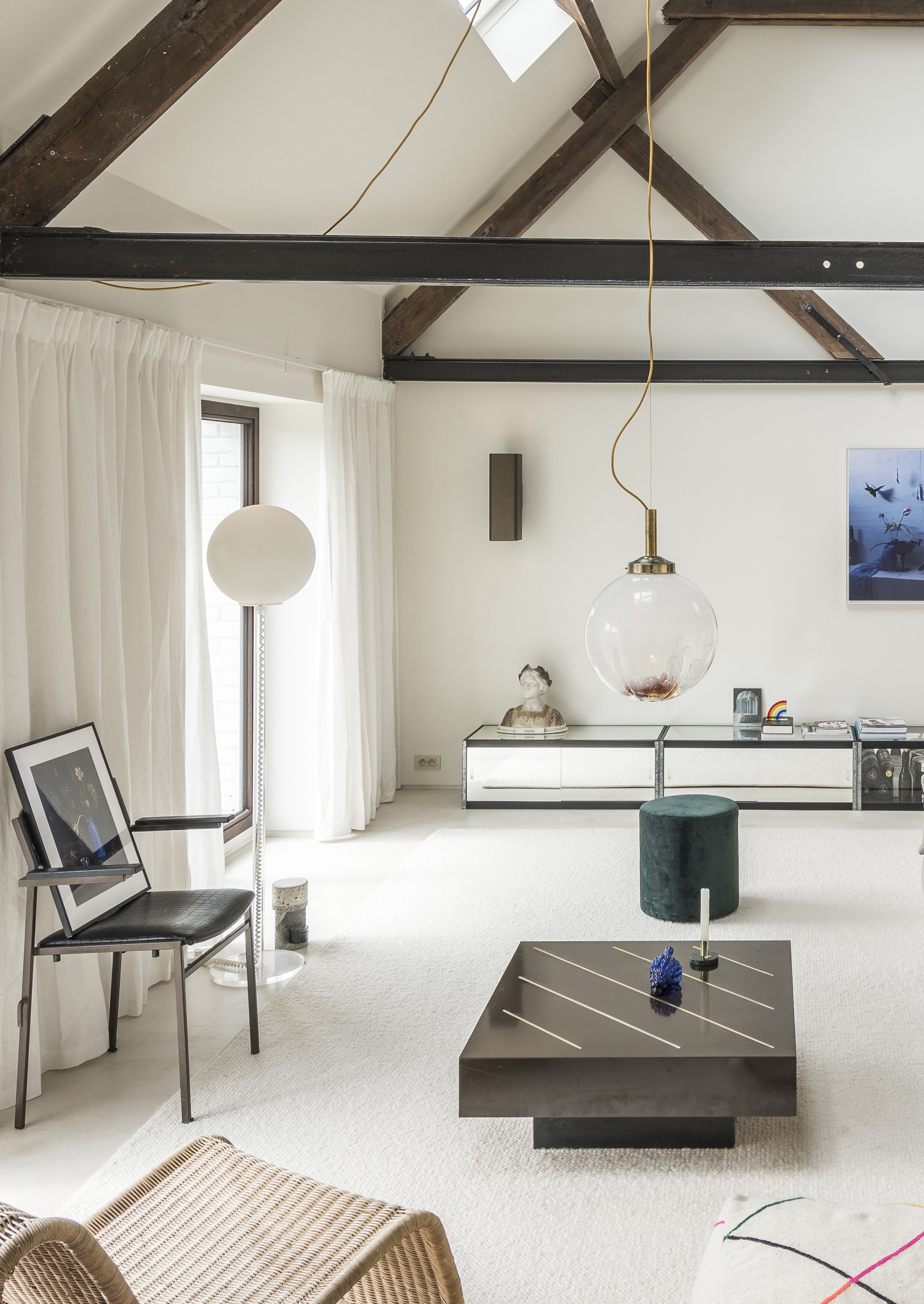 Living room with exposed timber roof trusses and spherical pendant light over carpeted floor