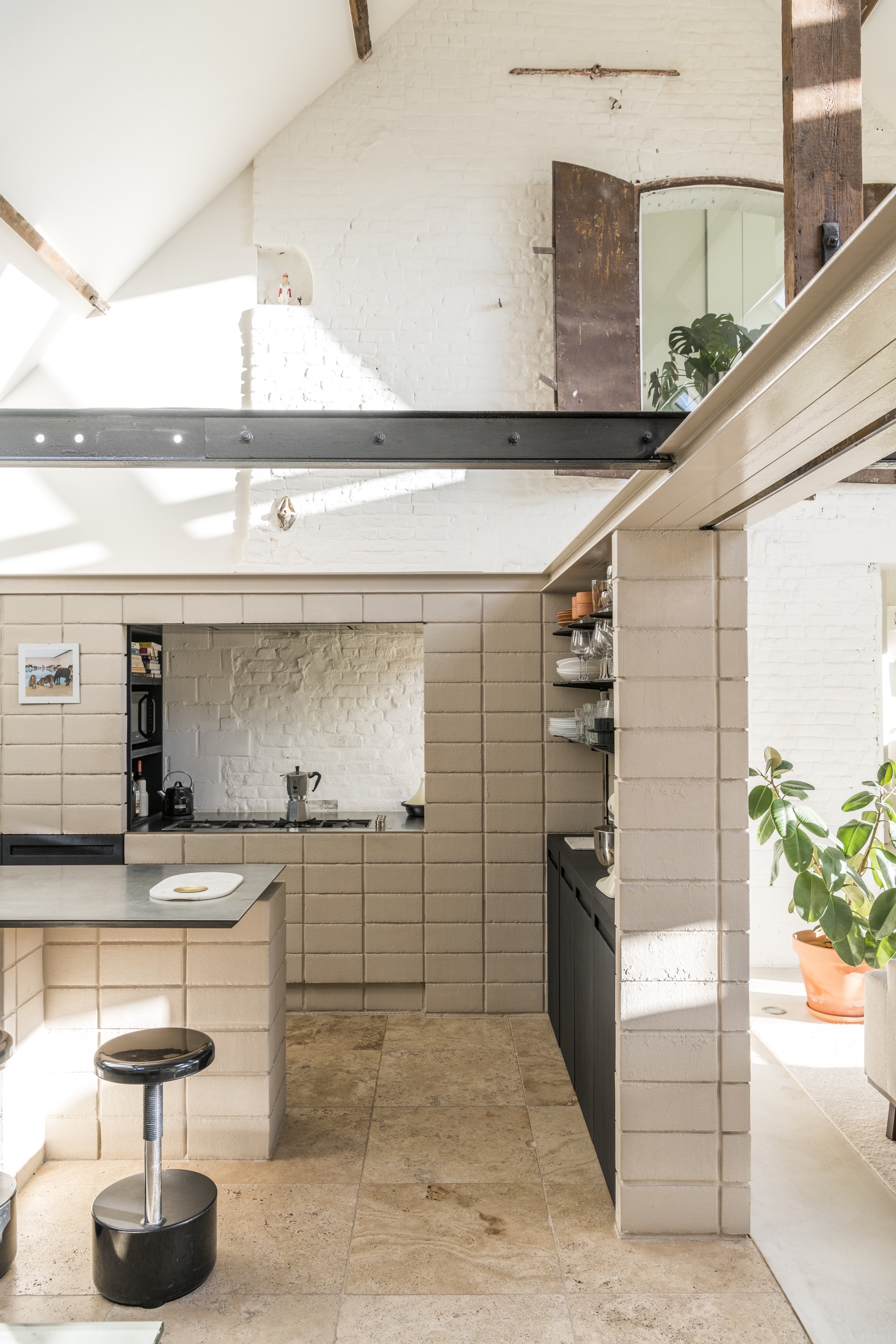 Kitchen with cream tile cabinetry and exposed whitewashed brick alcove under skylights