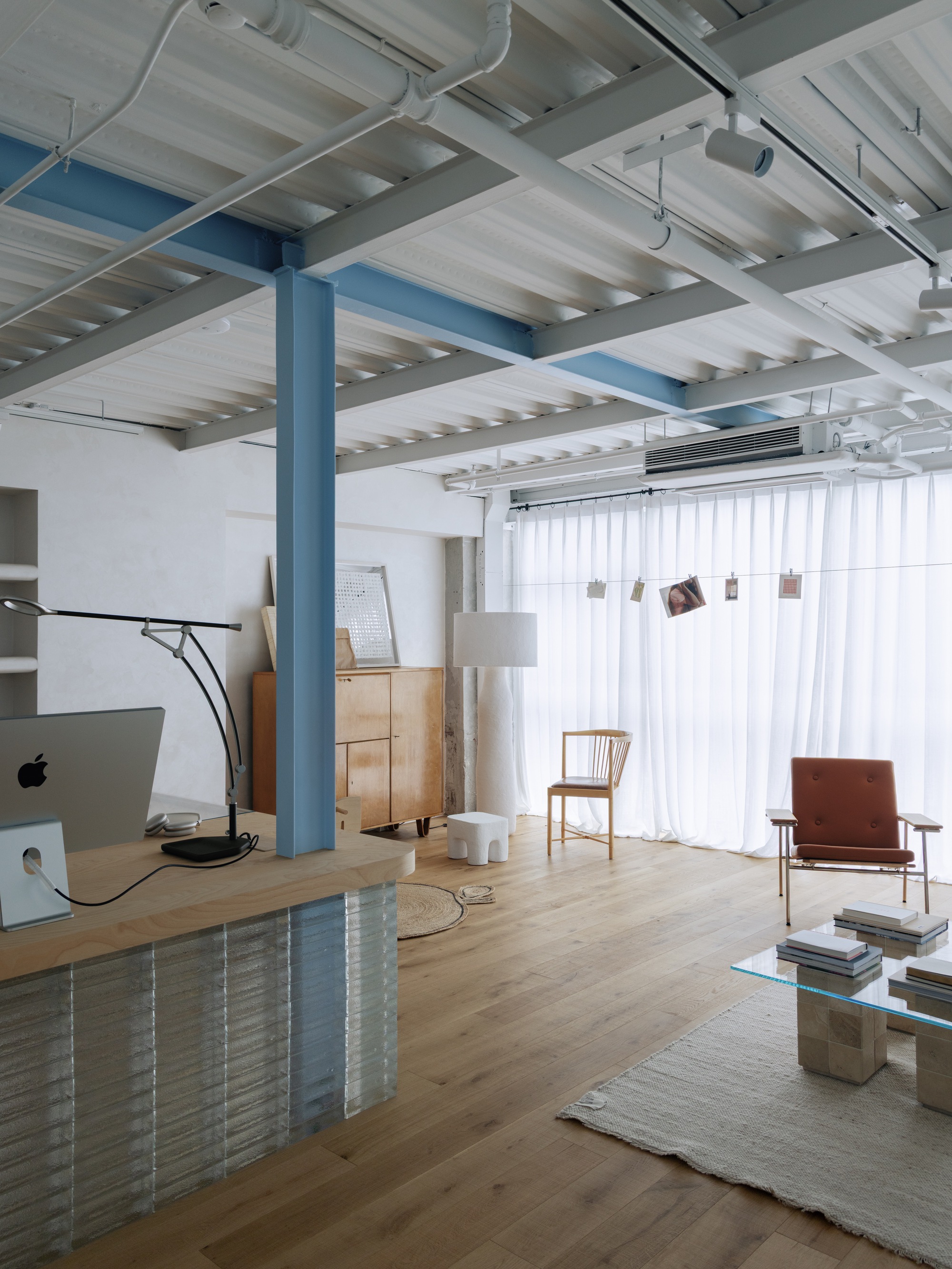 Living area with blue steel column and white ribbed ceiling structure above timber flooring