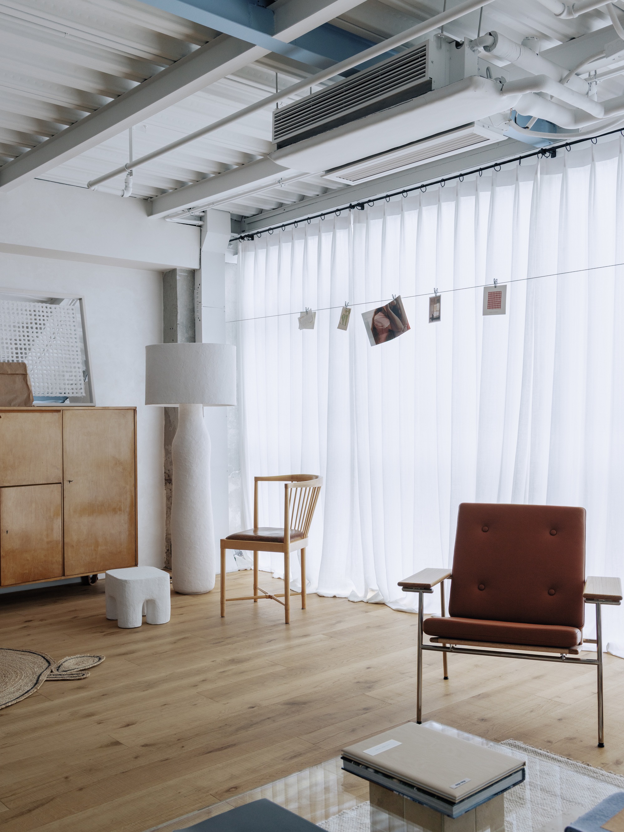 Close-up of white curtain room divider with photographs clipped to a suspended wire