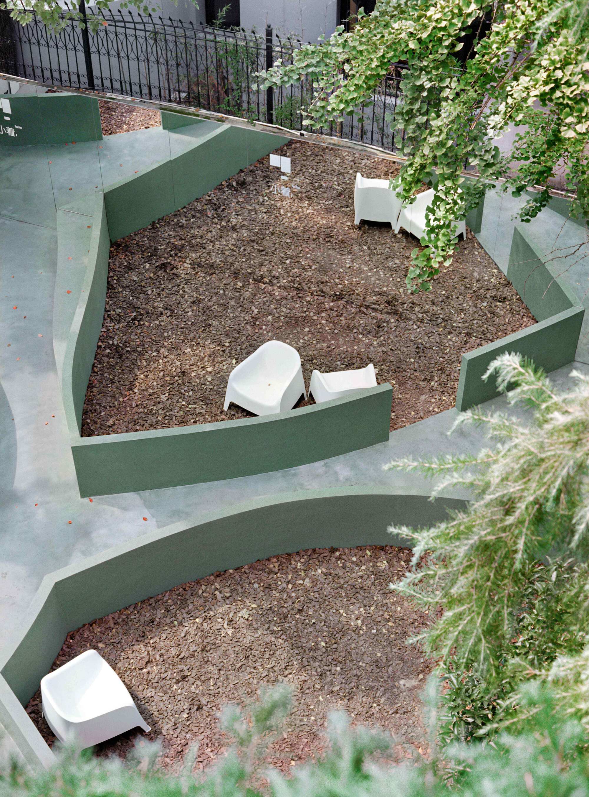 Aerial view of terraced courtyard with green painted steps, gravel beds and climbing vines