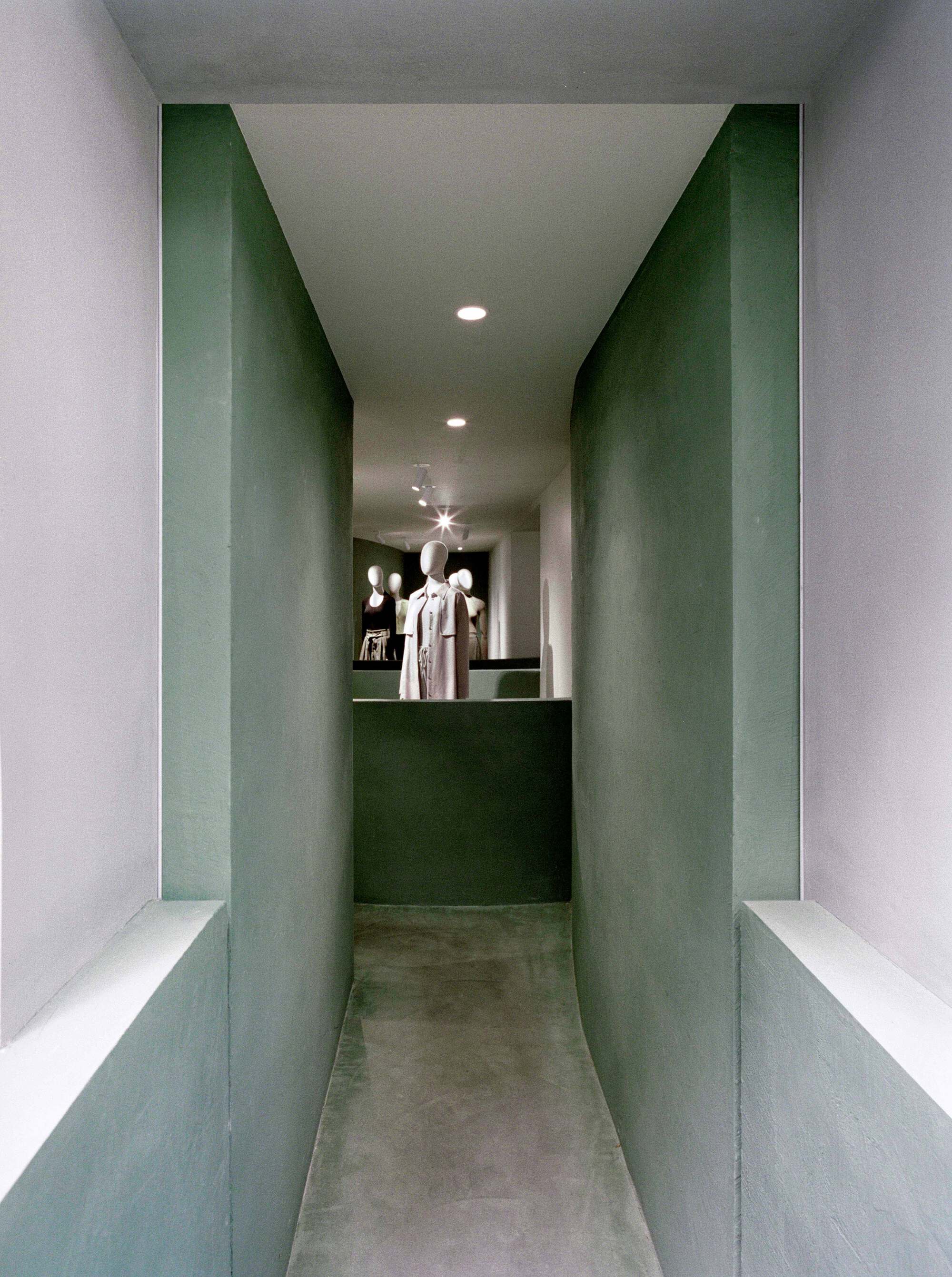 Narrow corridor with green plaster walls leading to a display counter at the end
