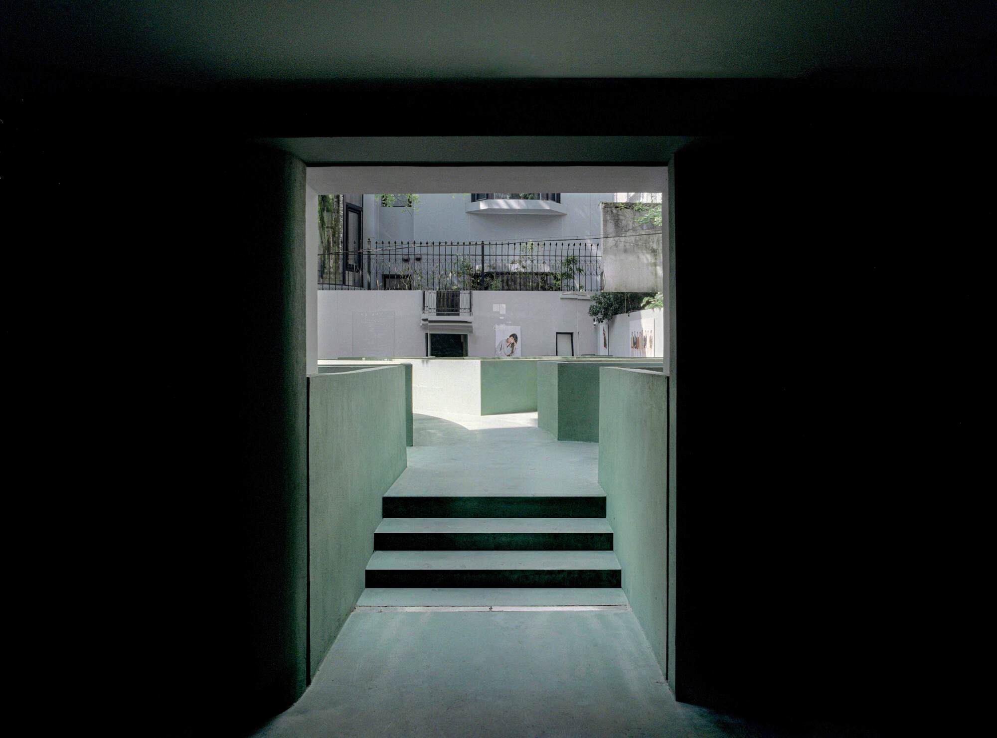 View through green plaster doorway to steps ascending toward a courtyard beyond