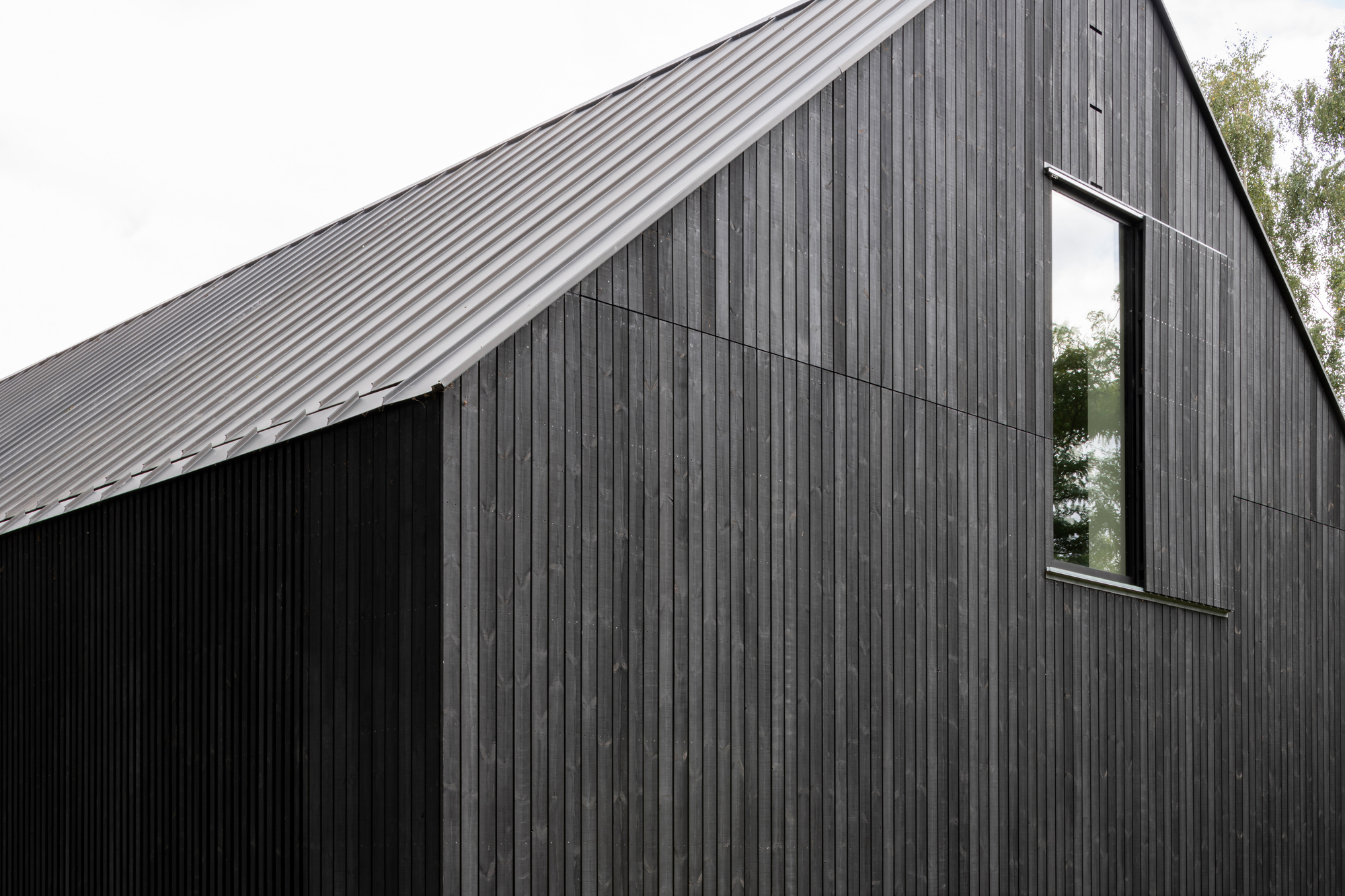 Close-up of the gabled form clad in vertical timber boards with a narrow vertical window