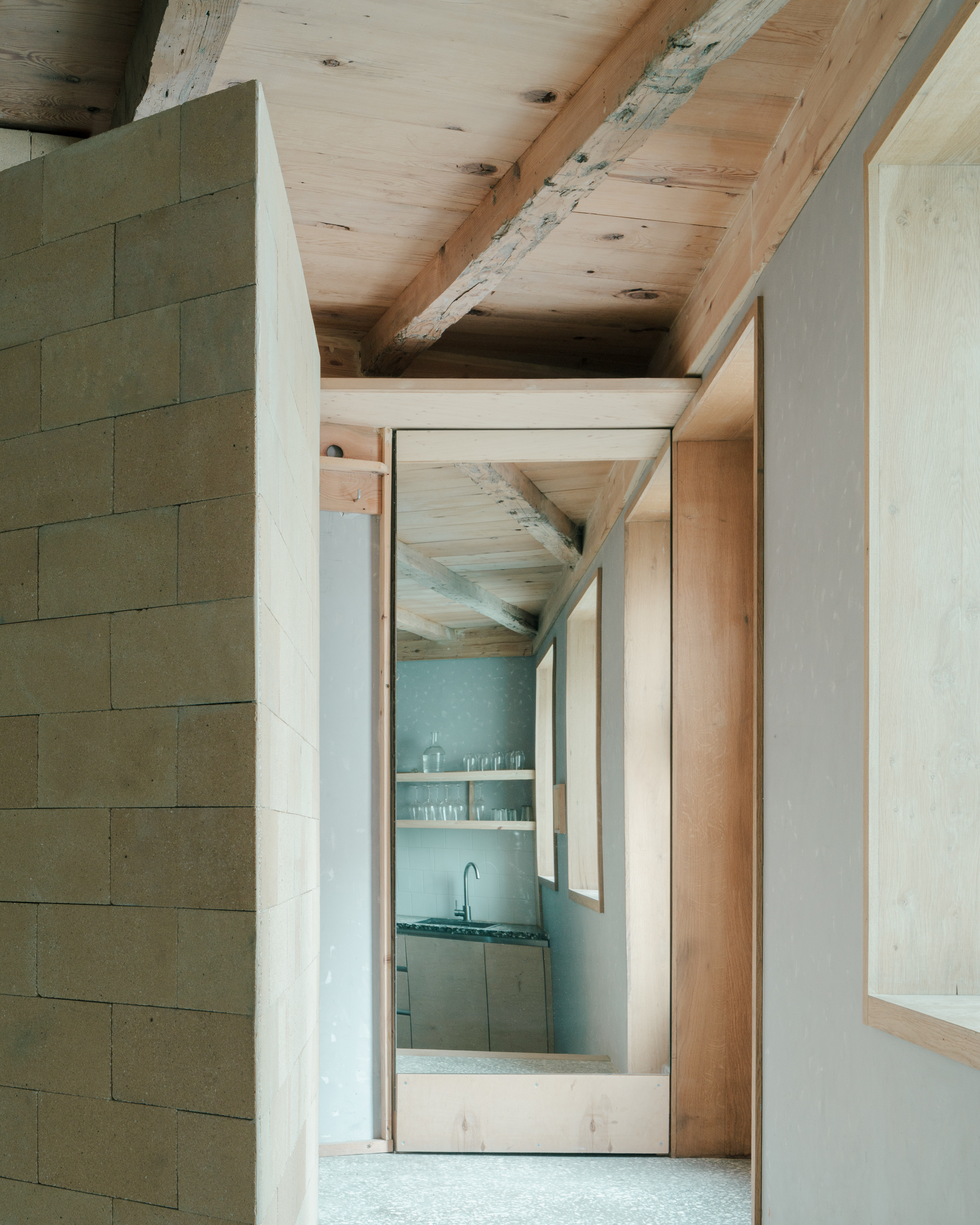 Interior passage with timber doorframe and glimpse of kitchen beyond plaster walls
