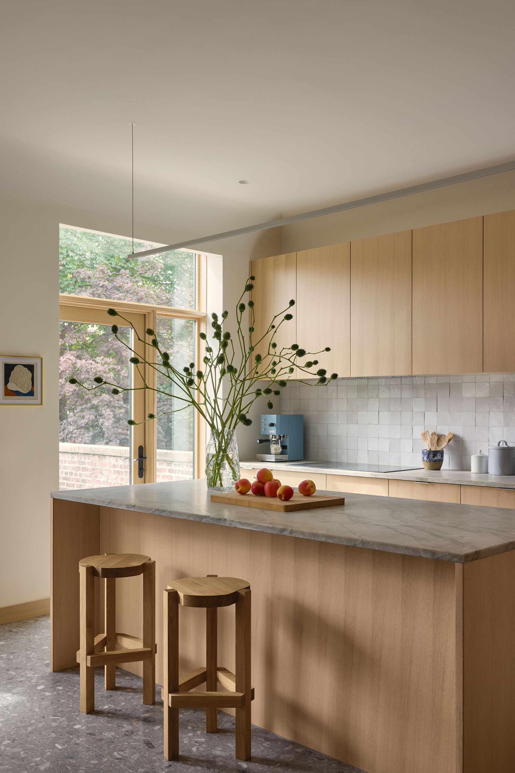 Kitchen island with stone countertop and timber cabinetry below clerestory window with garden view