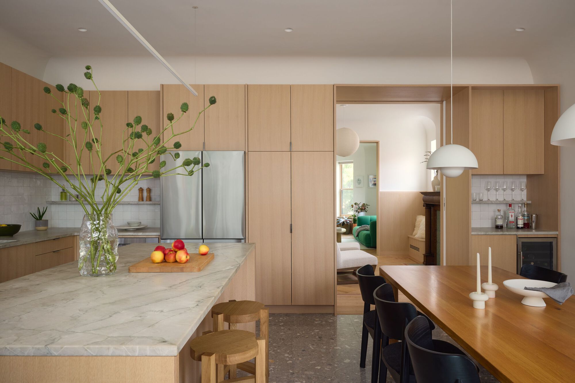 Open kitchen with marble island, oak cabinetry, and view through doorway to adjacent living space