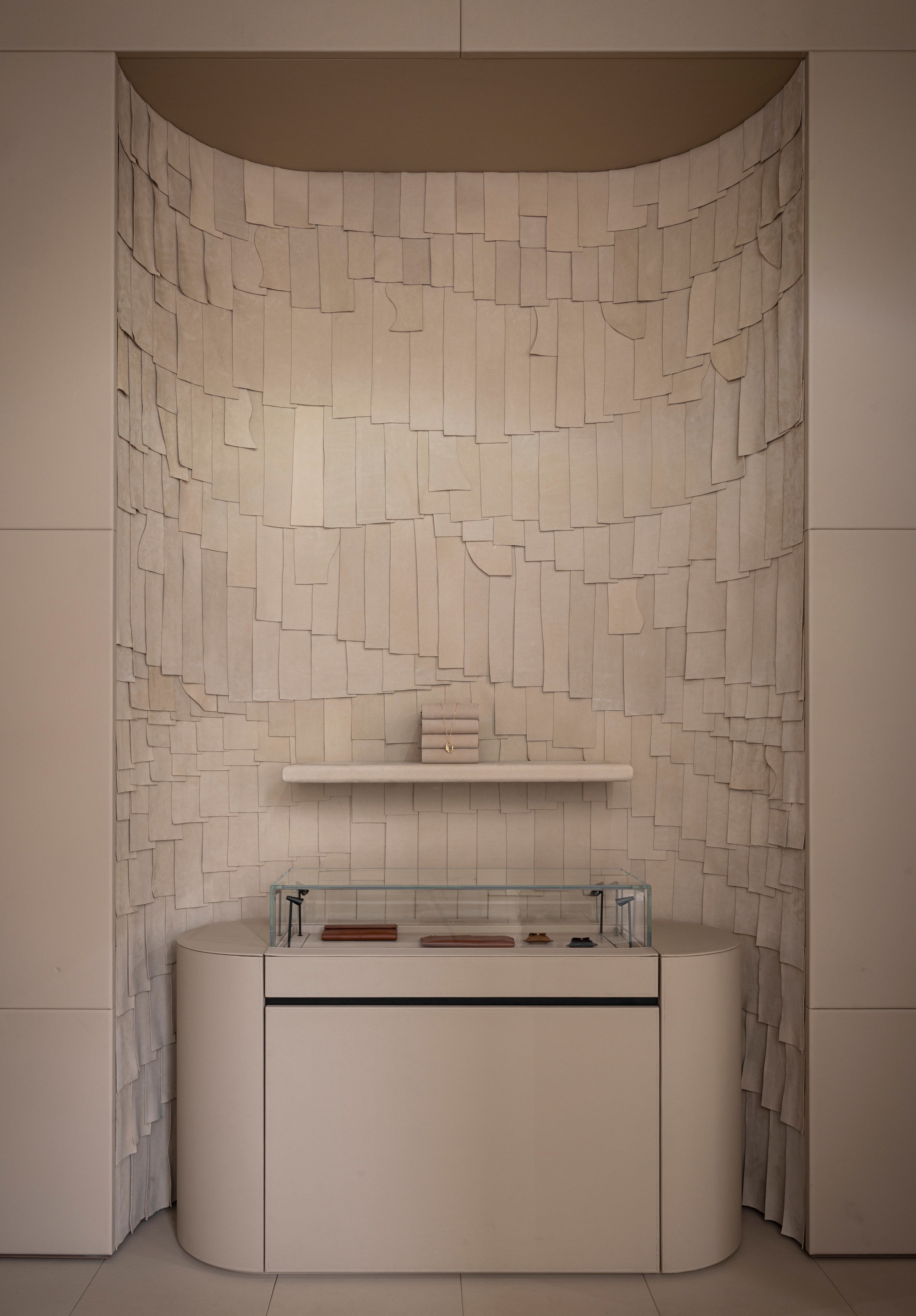 Curved alcove with irregular beige tile mosaic wall above a vanity with glass countertop