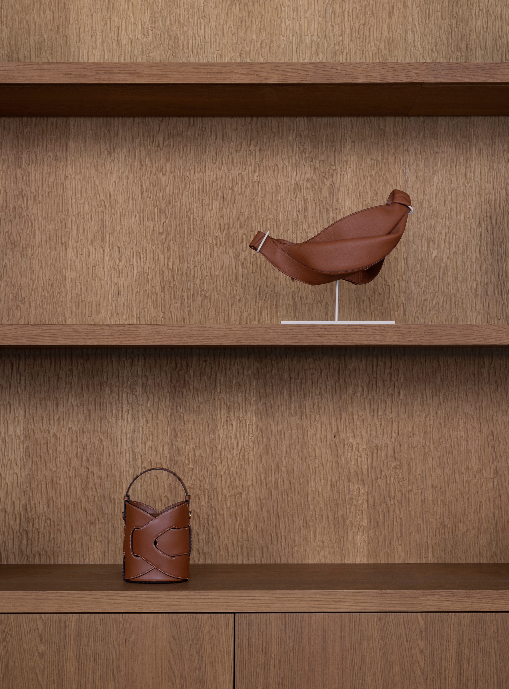 Built-in shelving with oak veneer displaying a sculptural bird form and leather vessels