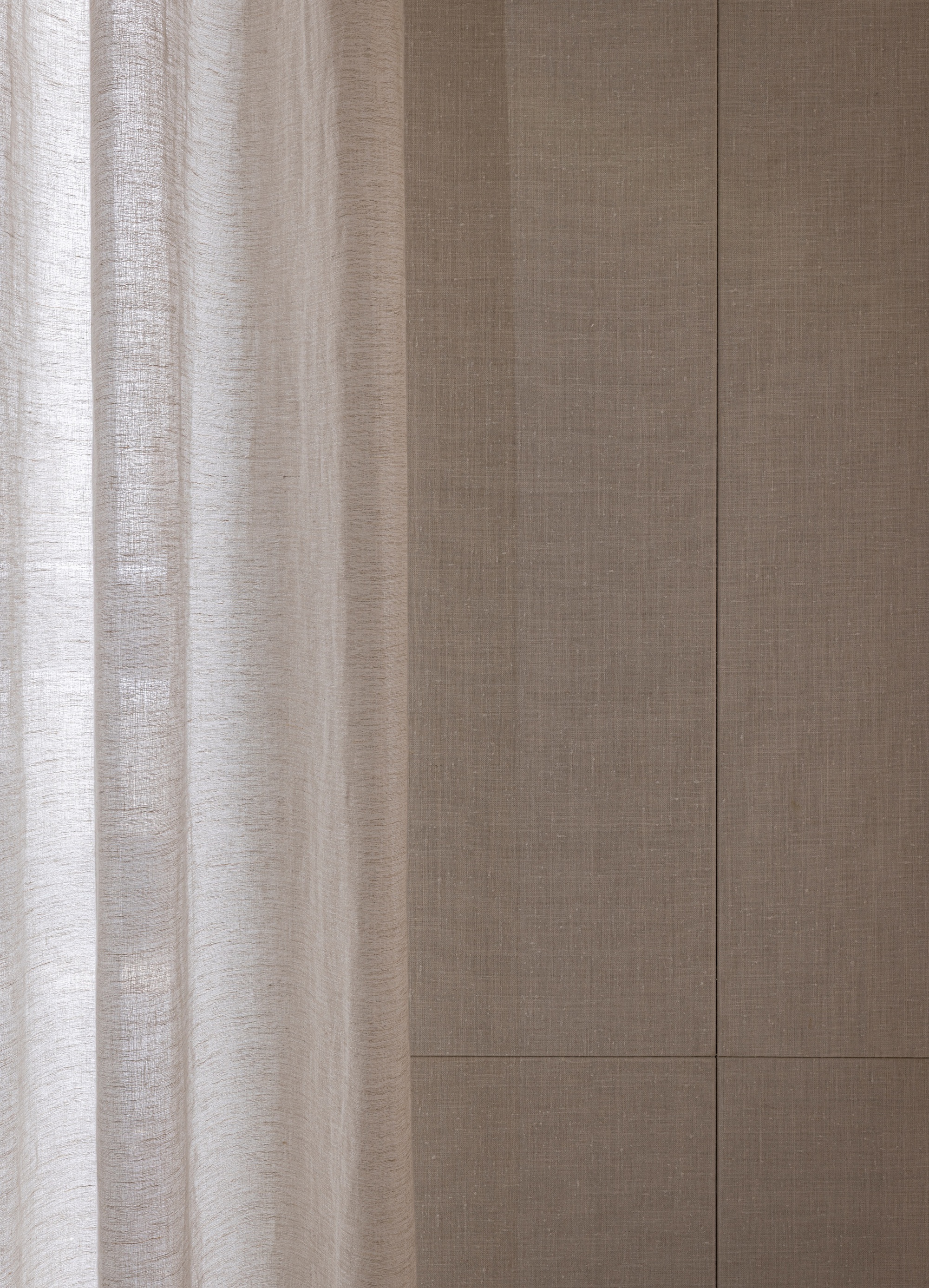 Linen curtain beside grooved oak wall panels with horizontal joint detail in natural light