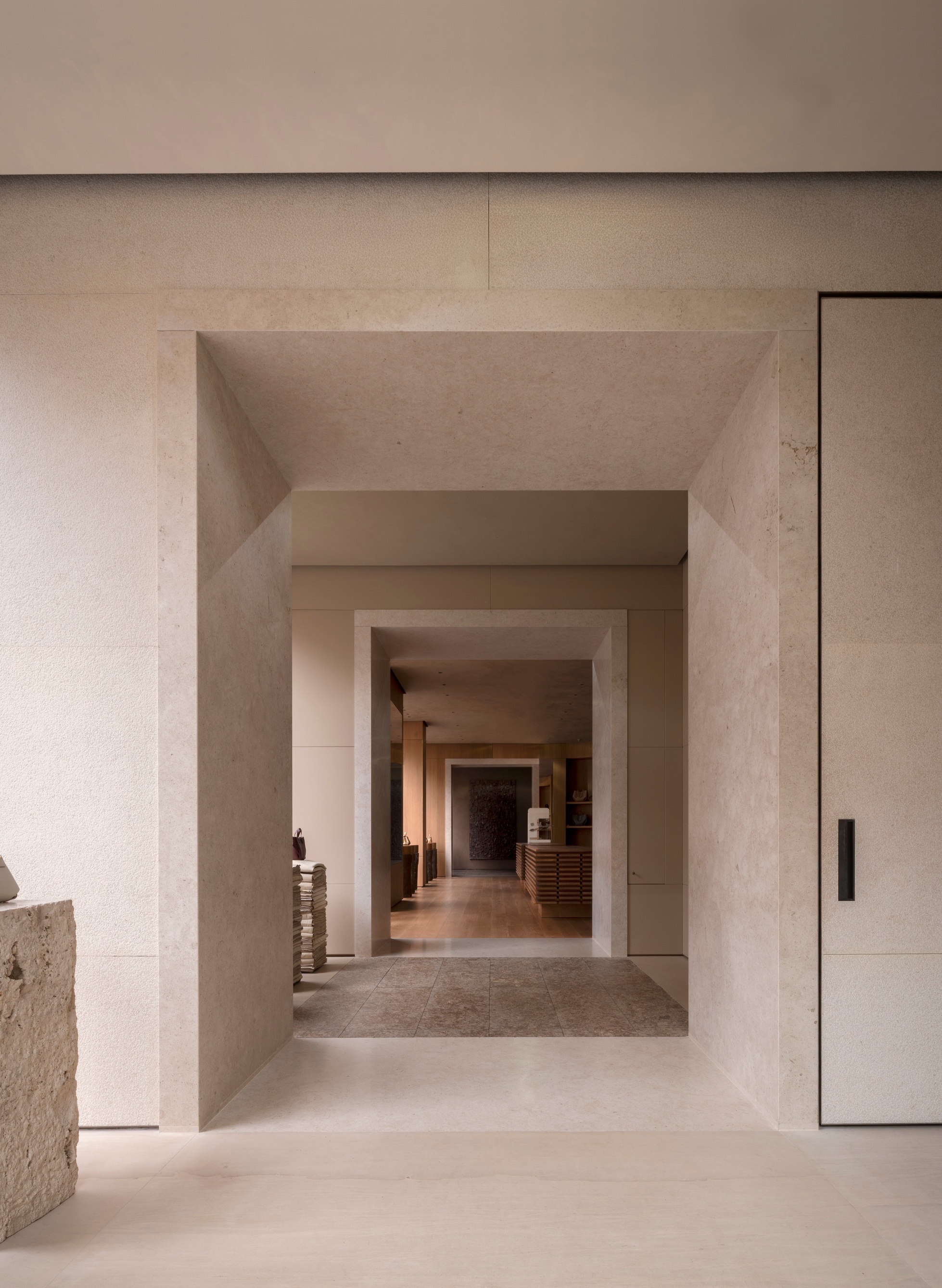 Sequence of thick stone portal frames receding through a gallery corridor with polished floors