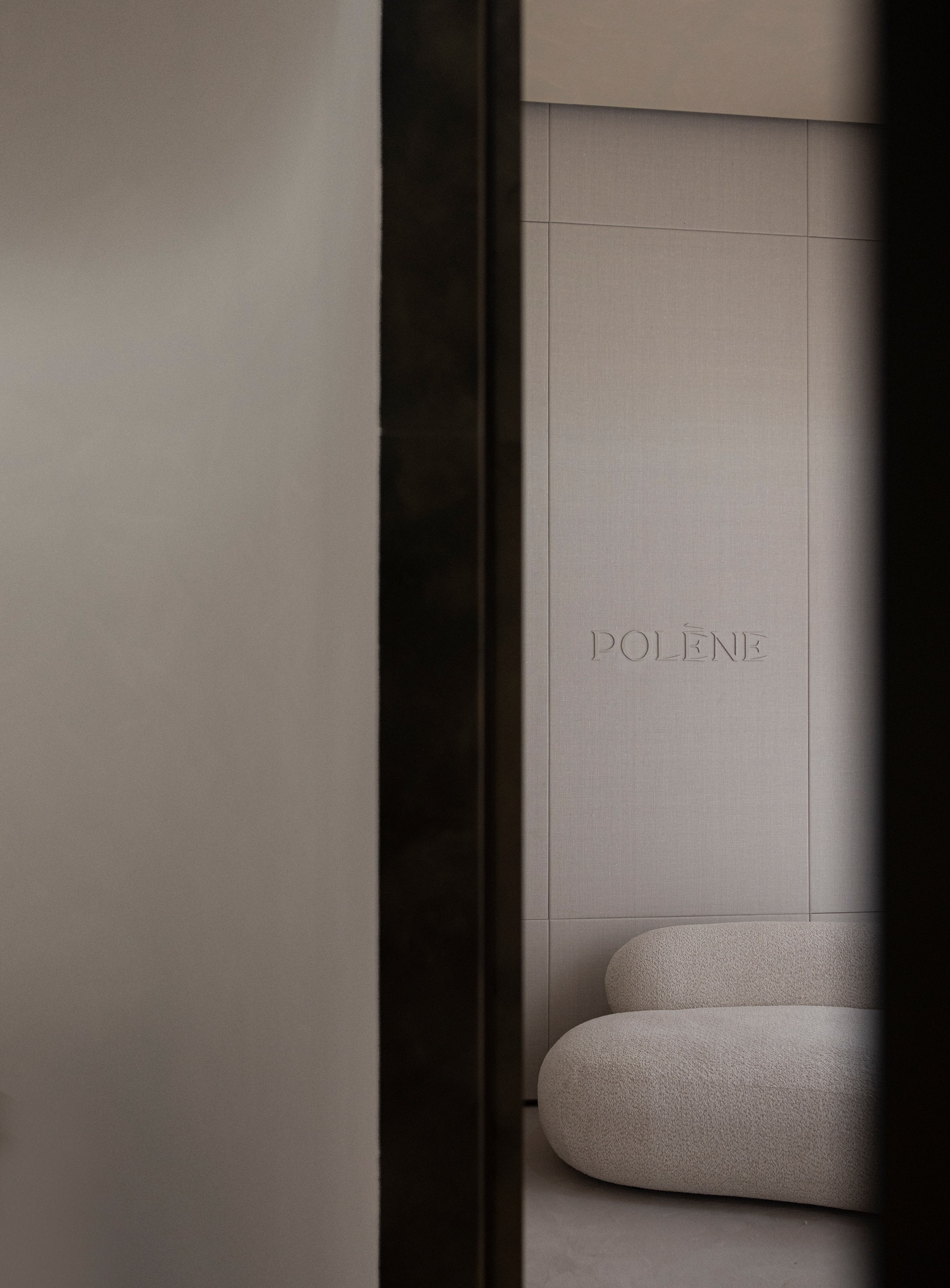 Partial view through dark doorway showing upholstered seating and engraved wall panel beyond