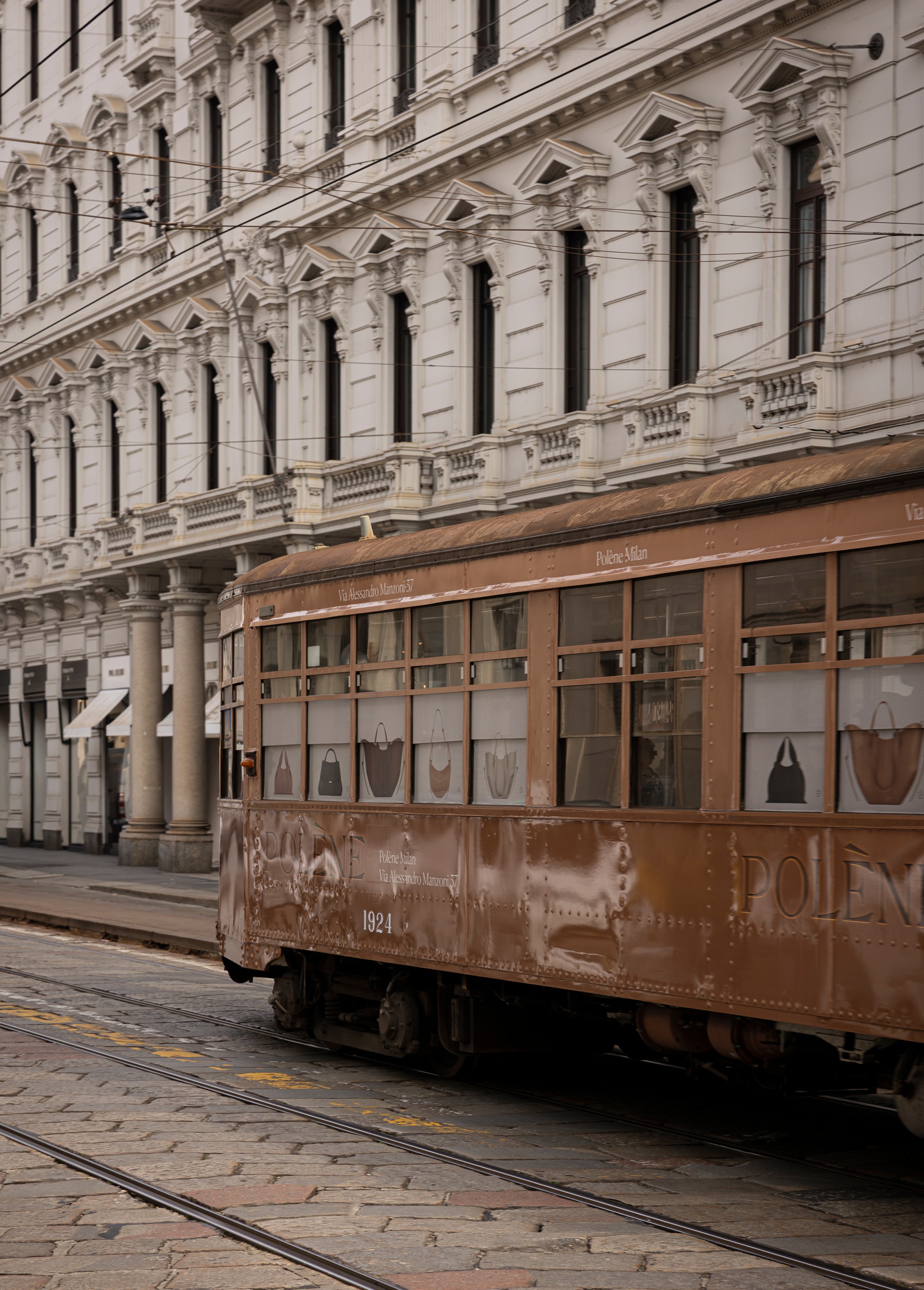Historic tramcar passing a cream stuccoed facade with tall windows and ornamental balustrading