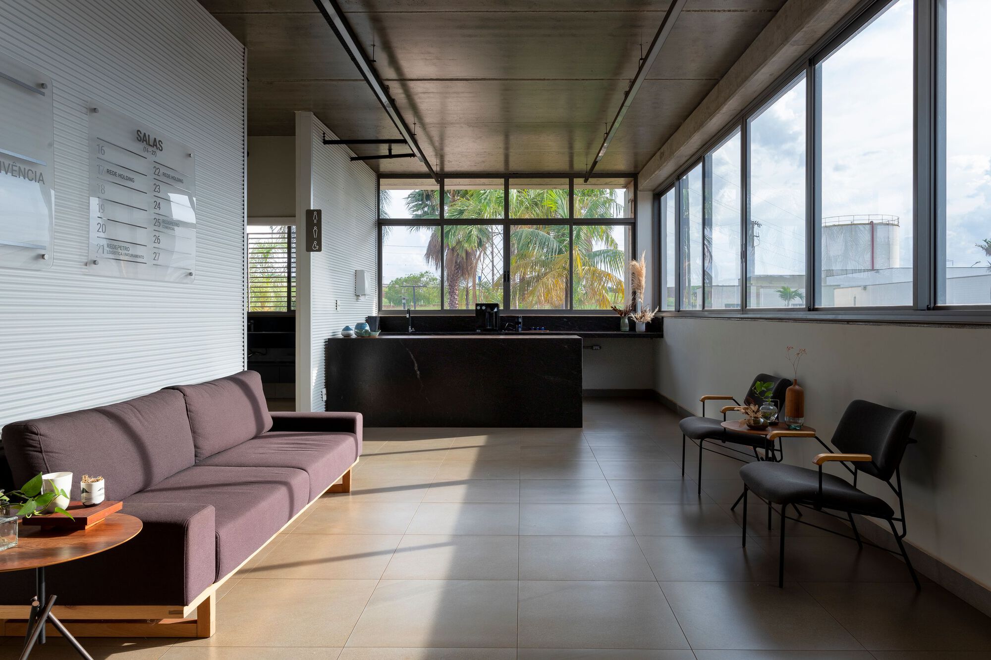 Reception lobby with large-format floor tiles and continuous glazing framing views of palm trees outside