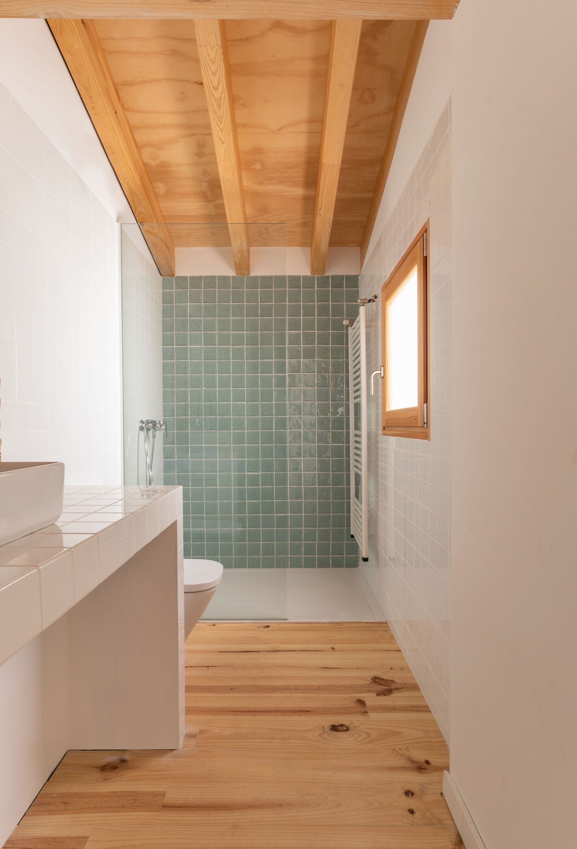 Bathroom with pale green tile shower enclosure, timber floor and exposed ceiling joists overhead