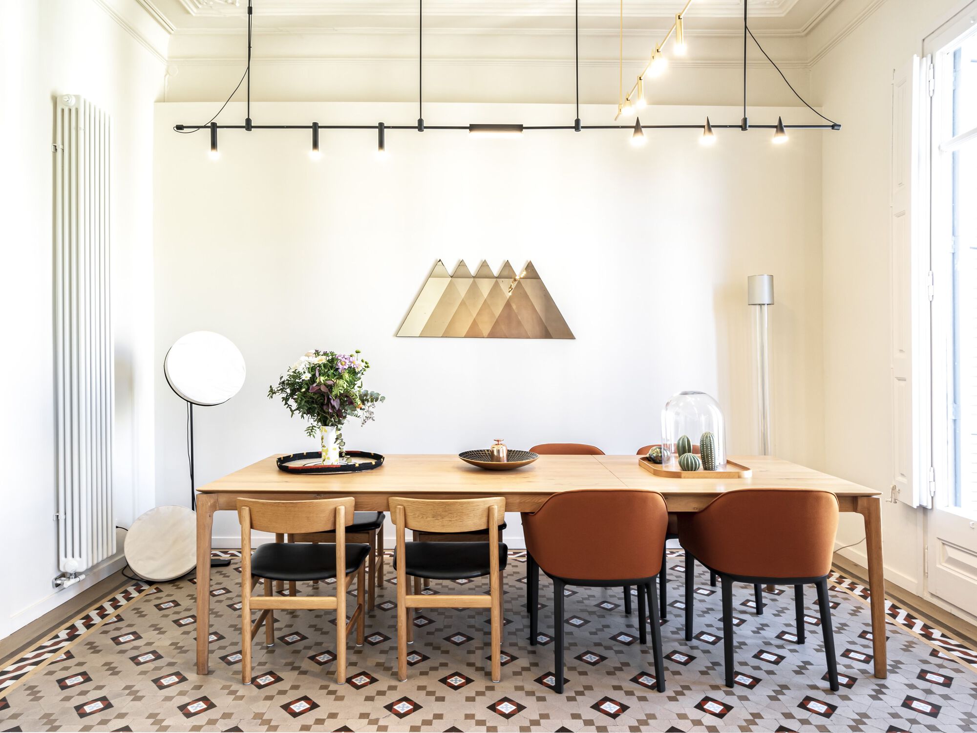 Dining area with timber table, mixed seating, and patterned tile floor under suspended track lighting