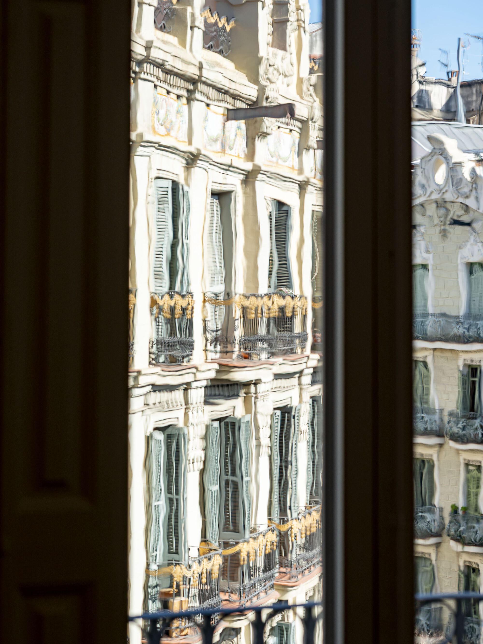 View through the window to the neighboring facades with ornamental balconies in afternoon sunlight