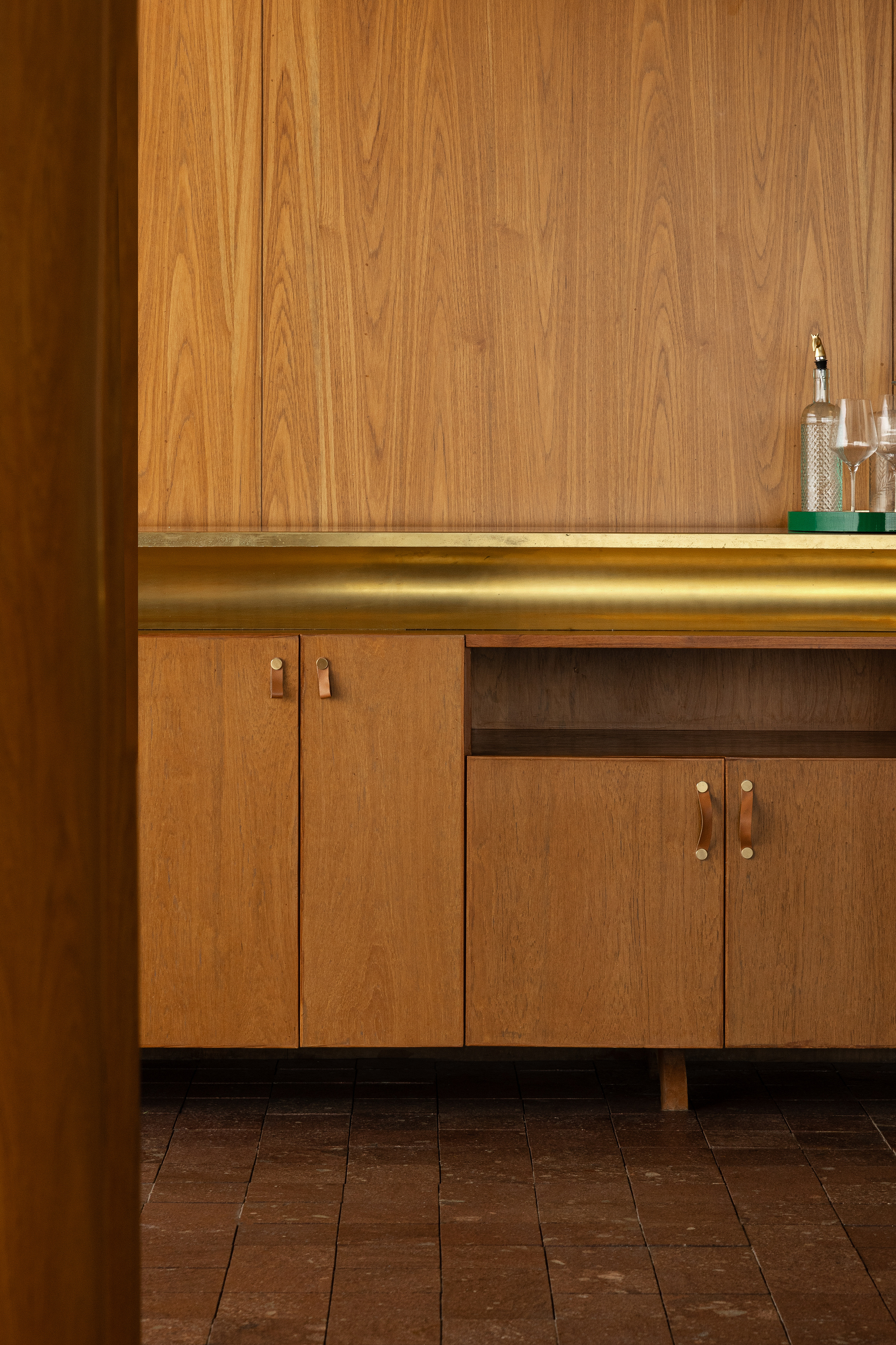 Close-up of walnut cabinetry with brass hardware and integrated LED strip lighting at countertop
