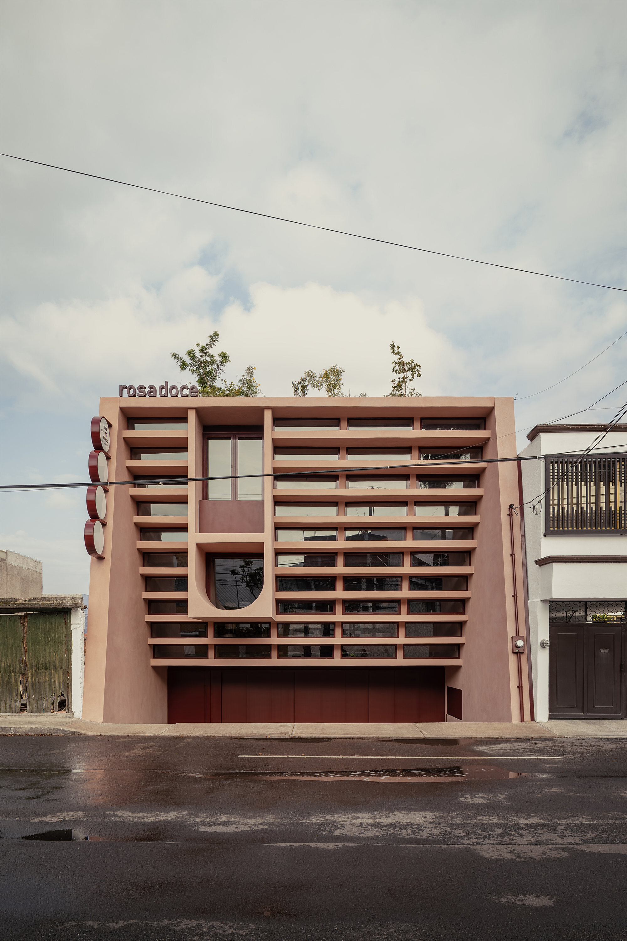 Frontal view of the layered facade screen with horizontal louvers under overcast skies