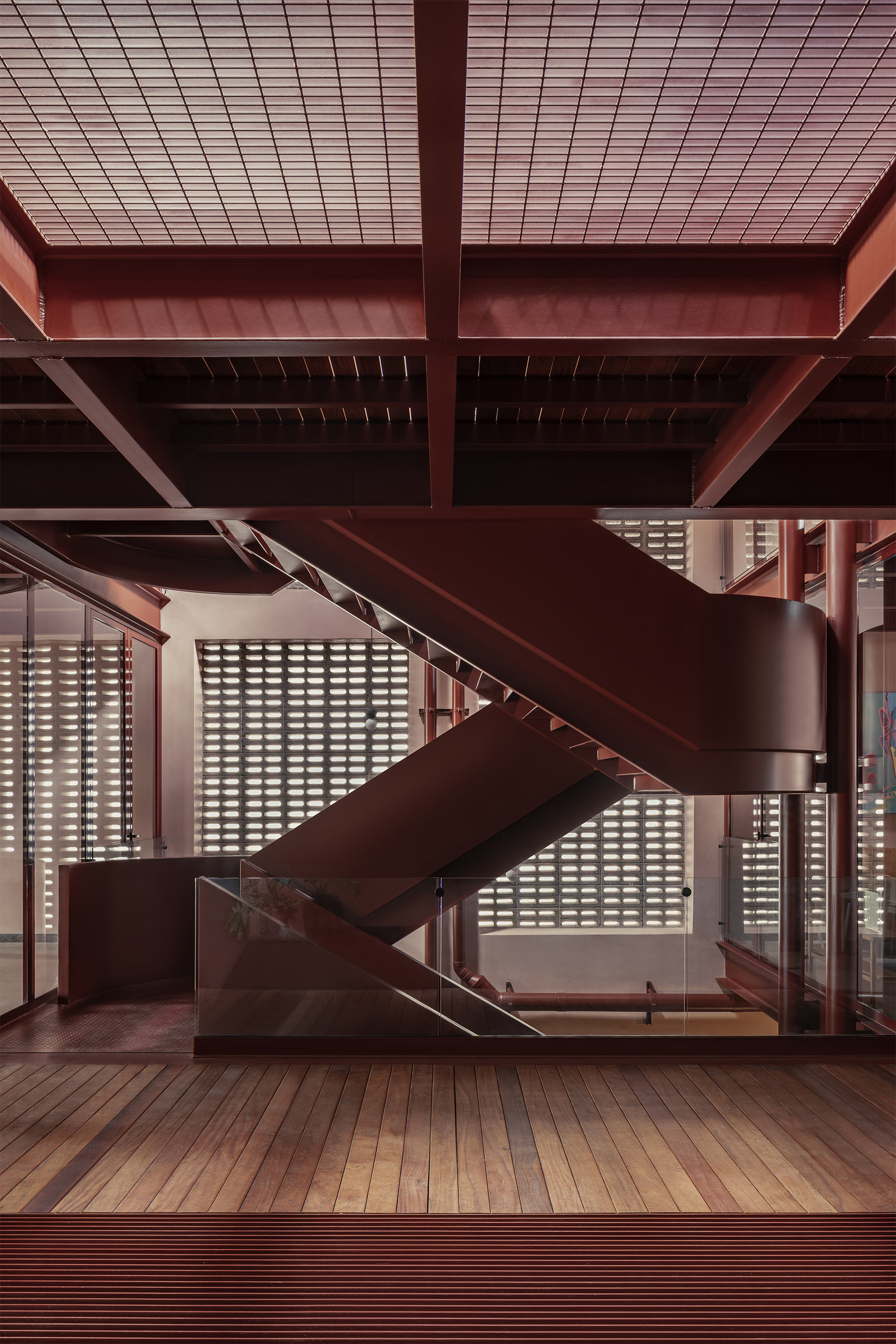 Central steel staircase with timber treads against a perforated block screen wall under exposed beams