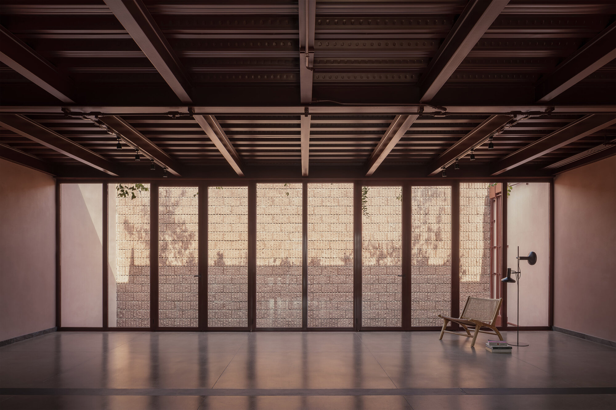 Gallery room with exposed timber joists and perforated block window wall with a single chair