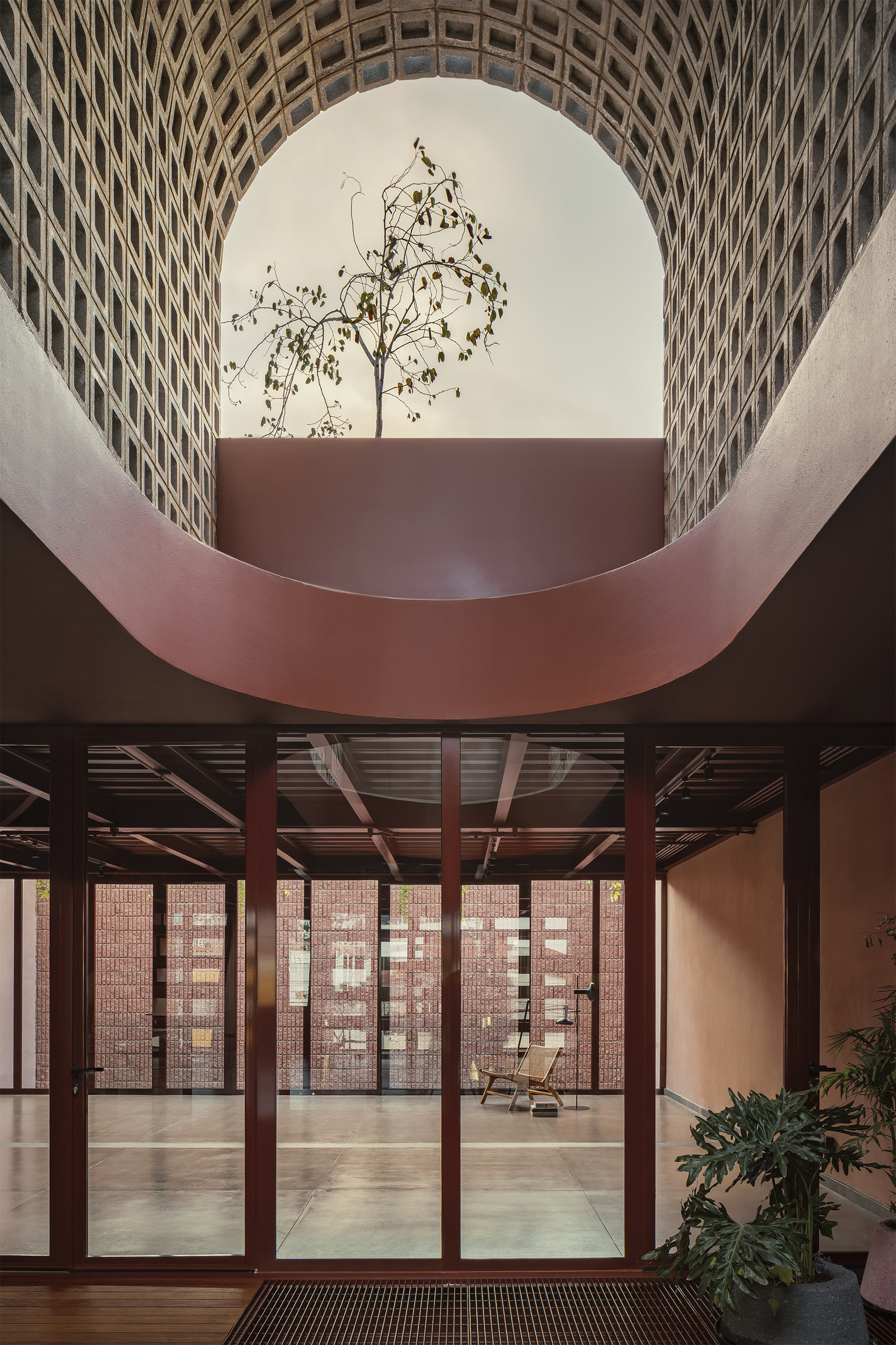 Curved void framing a tree with perforated brick screen and glazed doors below