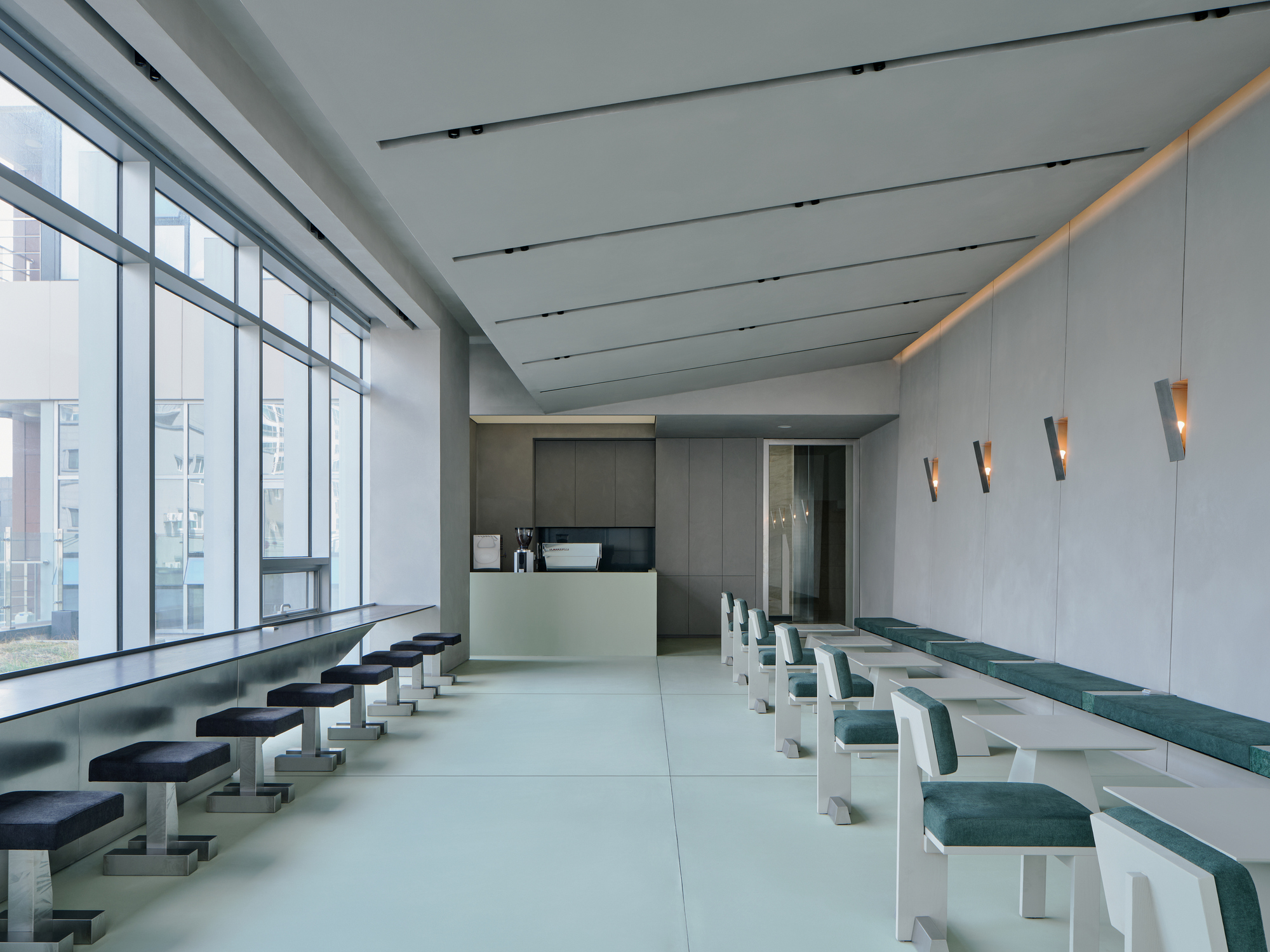 Reception desk with backlit frosted counter and dark grey joinery beneath linear ceiling slots
