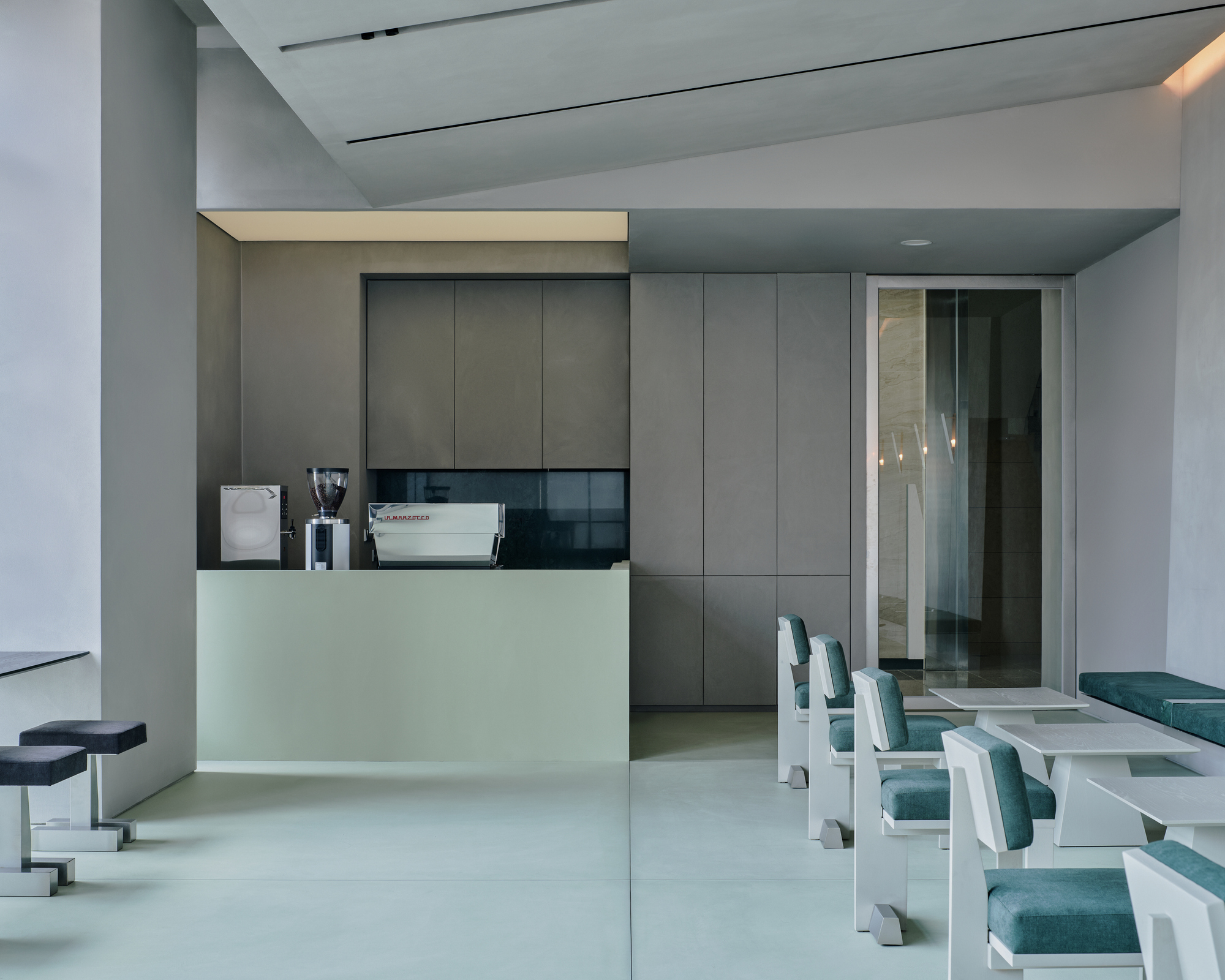 Service counter with integrated espresso machine and frameless glass doorway to adjacent space