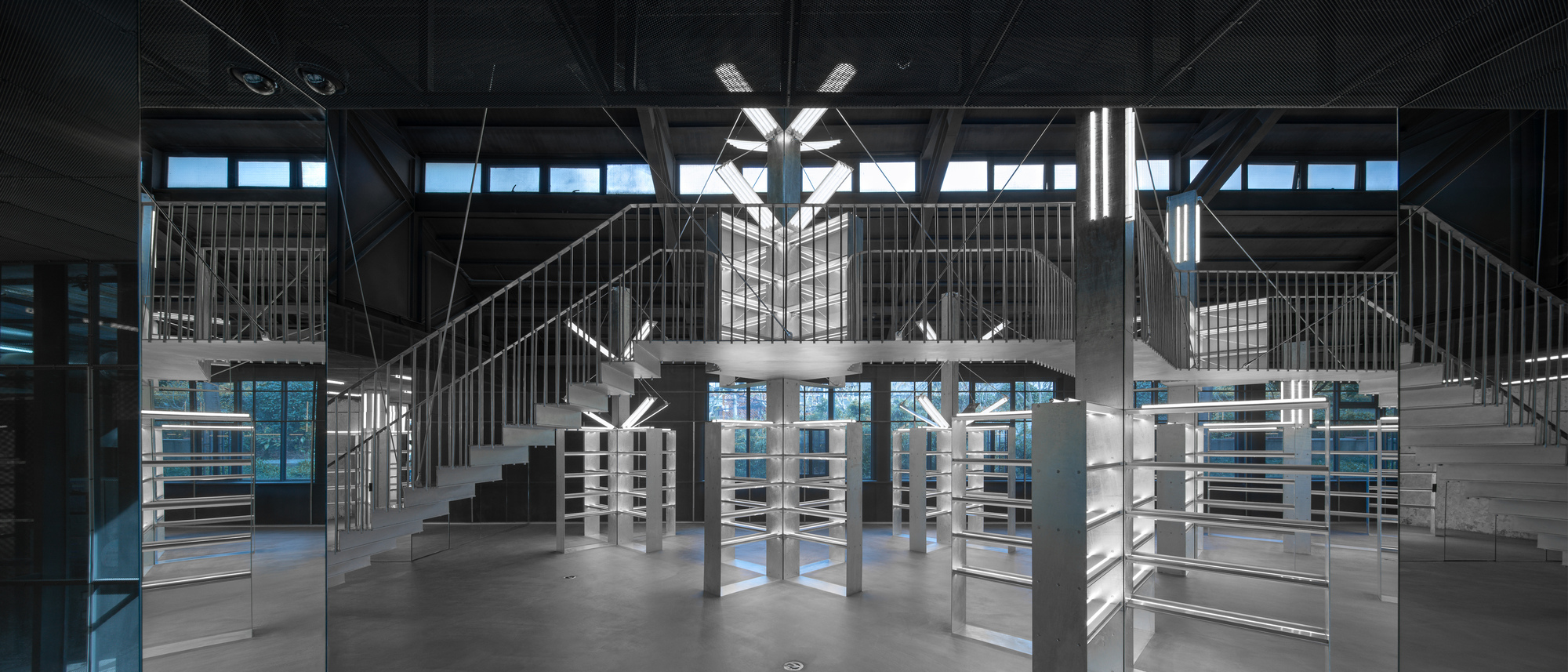 Double-height interior with symmetrical staircases, exposed steel trusses and blue-hour light through glazing