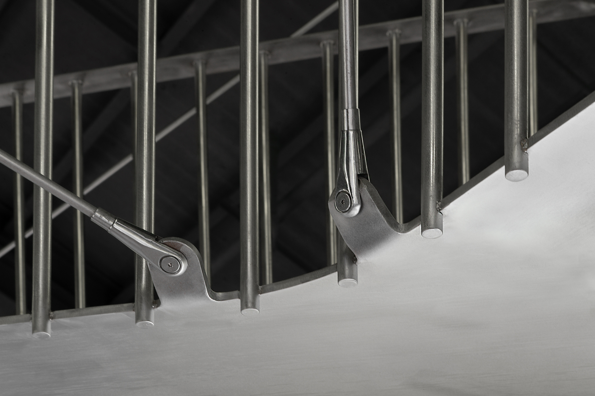 Upward view of cylindrical steel handrails cantilevering from curved concrete stair treads