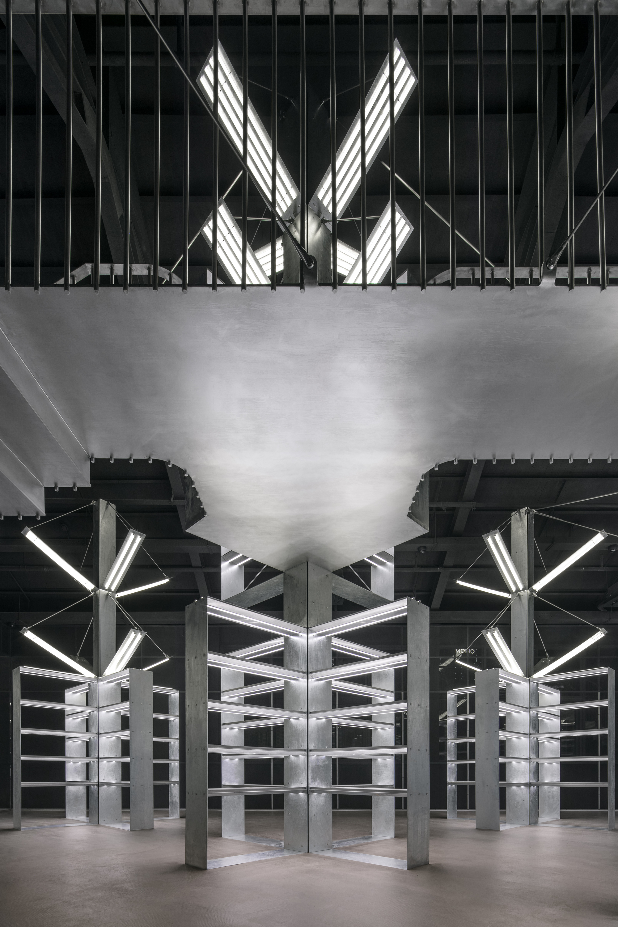 Symmetrical view of white metal shelving units beneath exposed structure and angular skylights