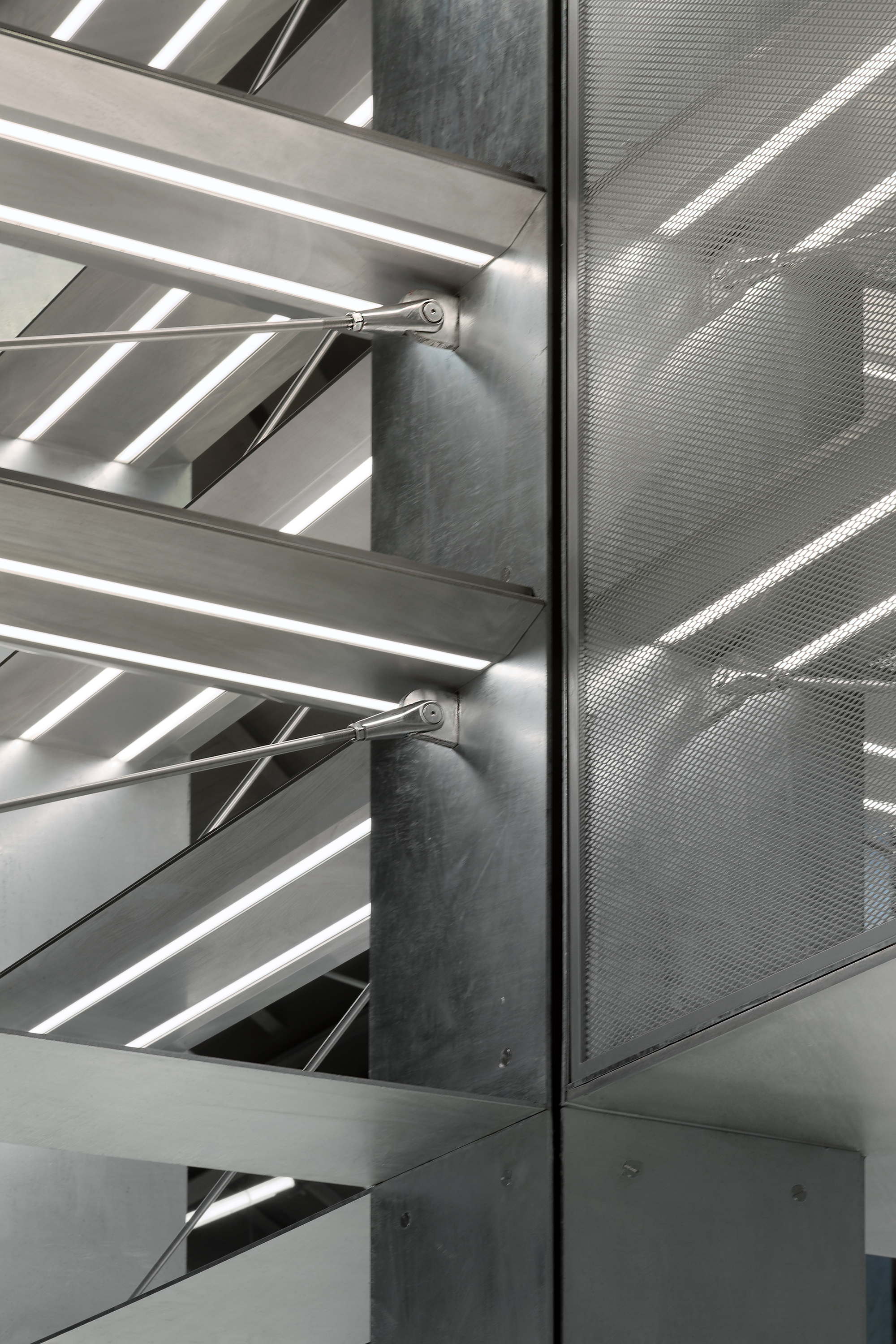 Detail of perforated metal panel meeting steel shelf supports at a concrete column