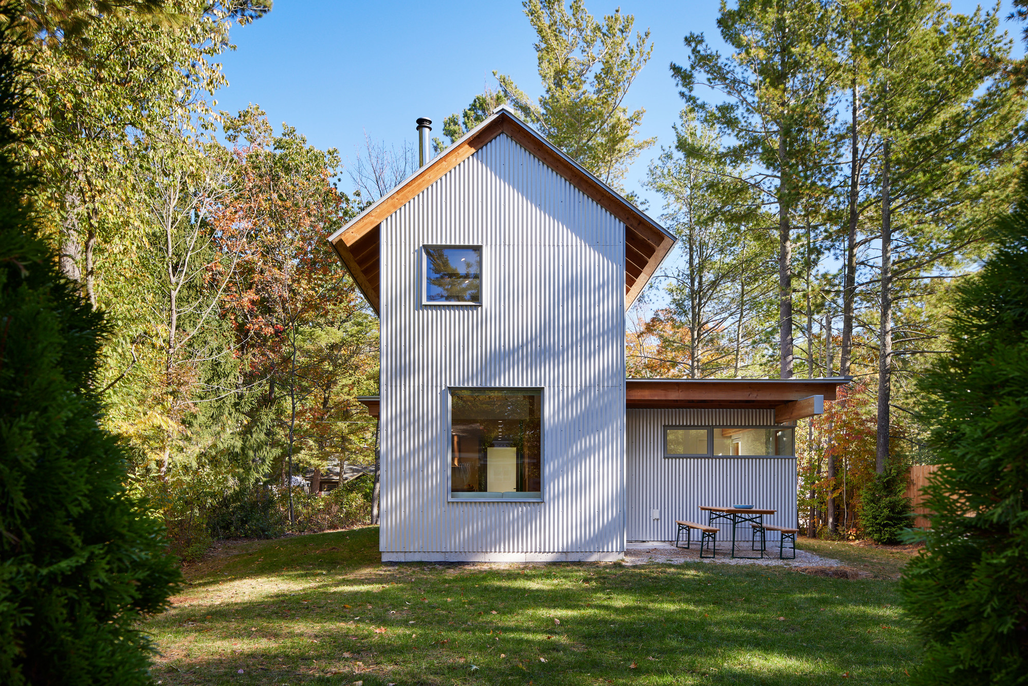 Rear facade showing corrugated metal cladding and single-story wing with outdoor furniture on grass