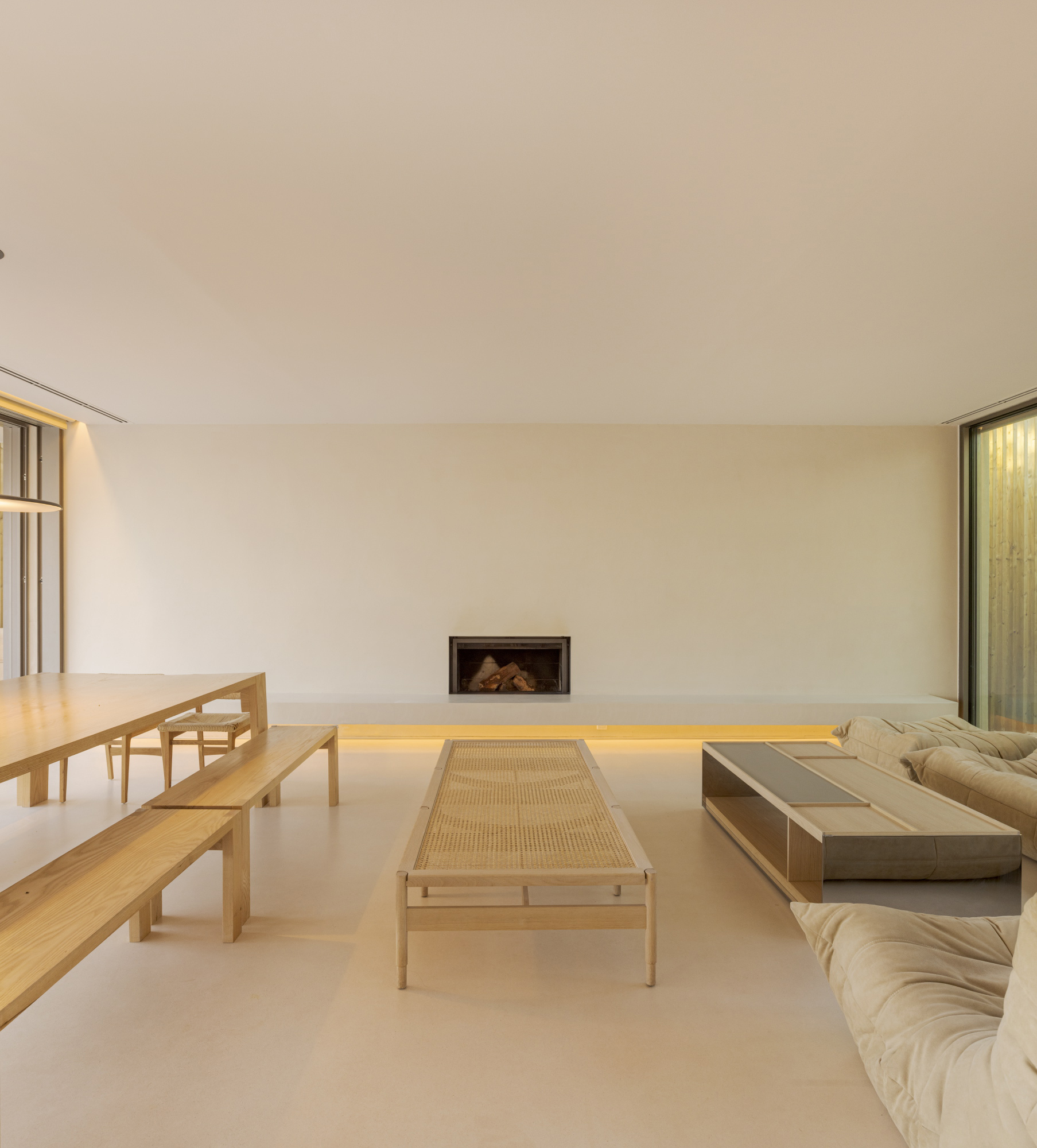 Living room with recessed fireplace, backlit floating bench and pale timber furniture under soft daylight